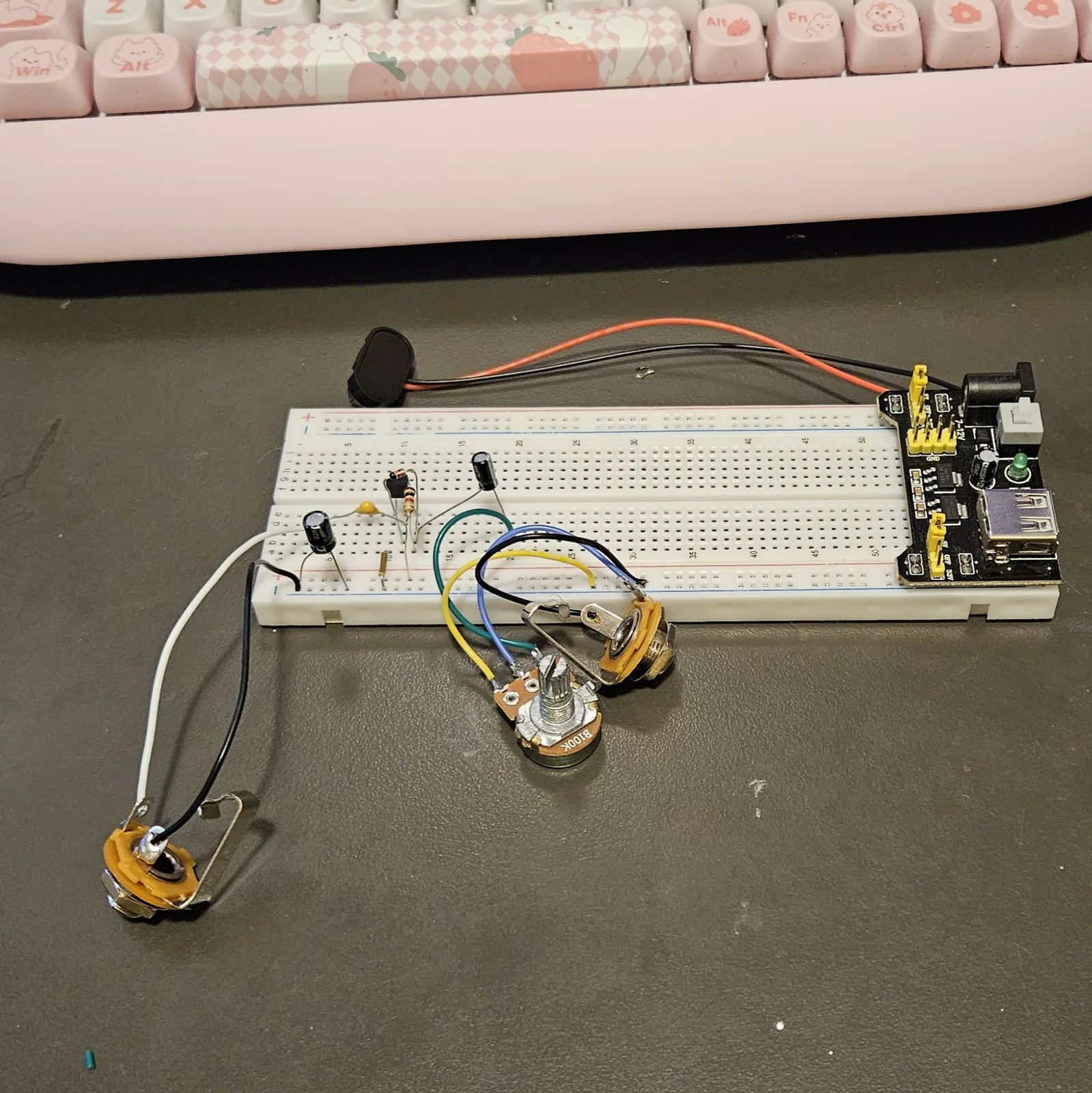 Both metal jack sockets now wired in, lying on the bench in front of the board on white and black leads, with the potentiometer and its blue, yellow and green leads between them and the breadboard.