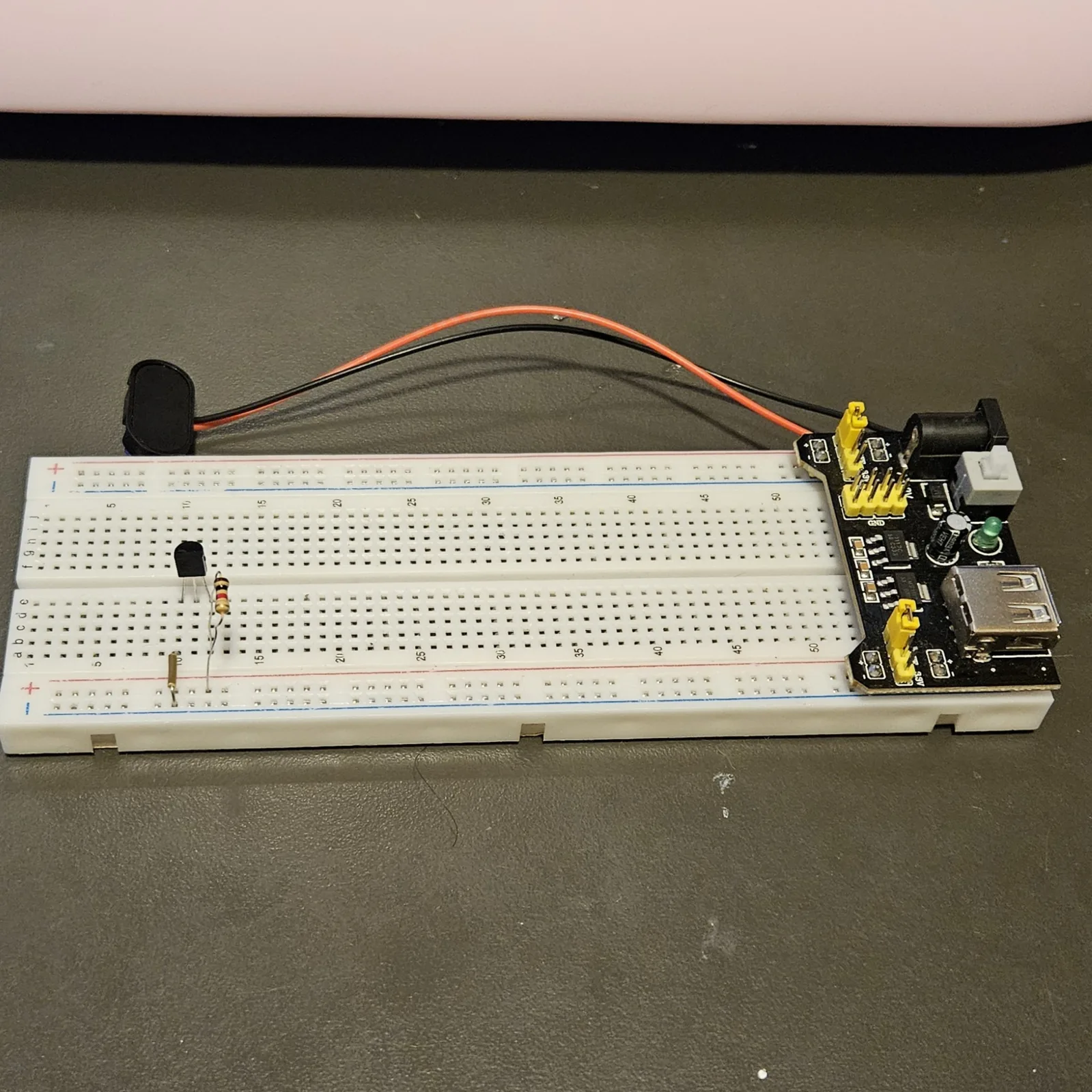 A banded resistor now lies across the rows beside the transistor and the diode, its leads bent flat into the board.
