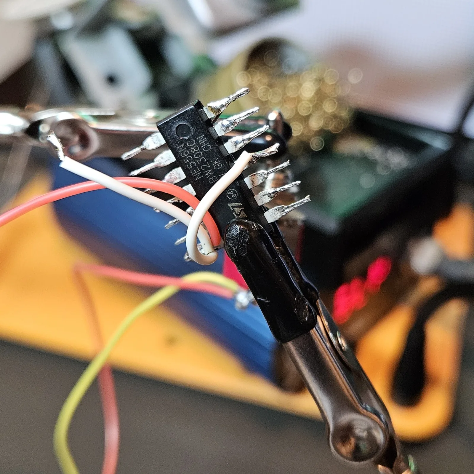 The reset jumpers soldered down, white wires arcing through the air from the reset pins over to the V-plus pin, with the red and black supply leads dangling below the chip.
