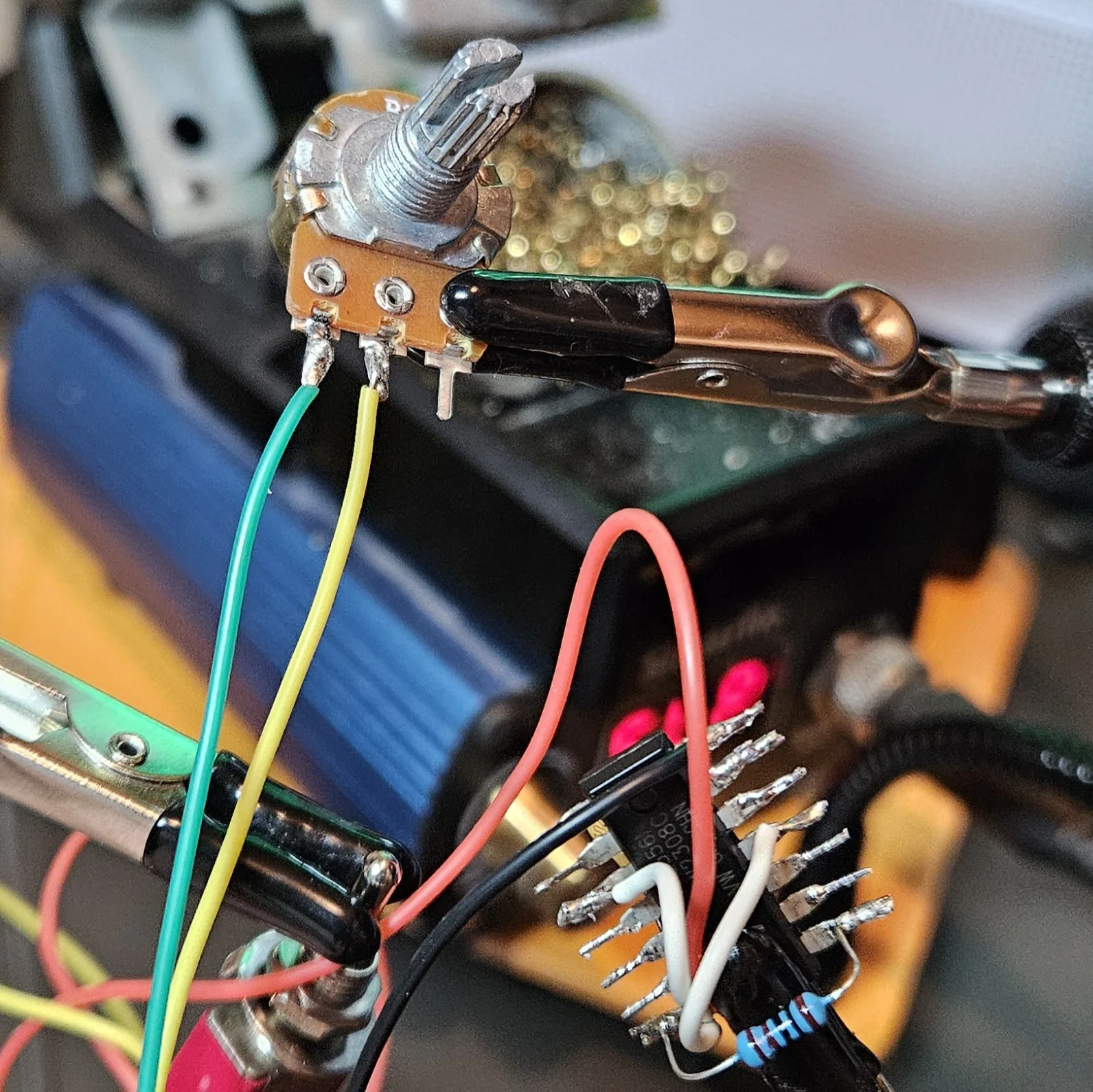 The B1M pitch potentiometer clamped in the helping hands with green and yellow flying leads soldered to two of its three lugs.