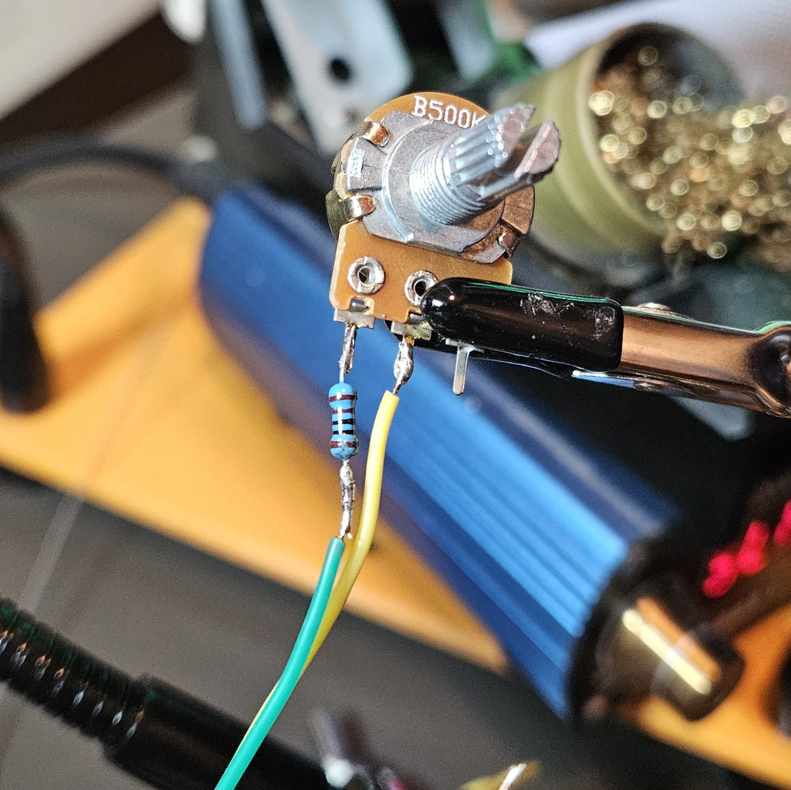 The B500K shape potentiometer with a blue 1K series resistor and green and yellow leads soldered to its lugs, prepped before mounting.