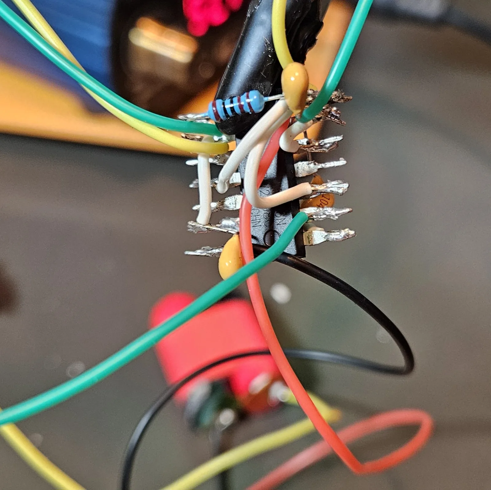 The finished guts: a dense spider of point-to-point wiring on the splayed NE556, with two yellow timing caps, the 1K resistors, white jumpers, and red, black, green, and yellow leads running out to the pots and jack.
