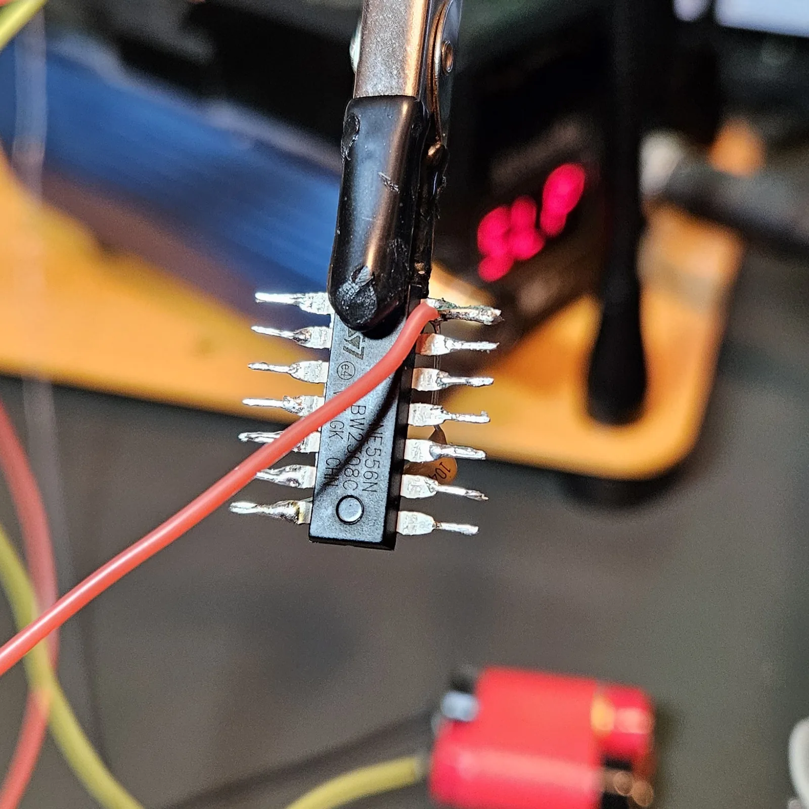 The red V-plus supply lead soldered to the chip's V-plus pin and left hanging down across the body, with the '104' decoupling cap visible between the pins.