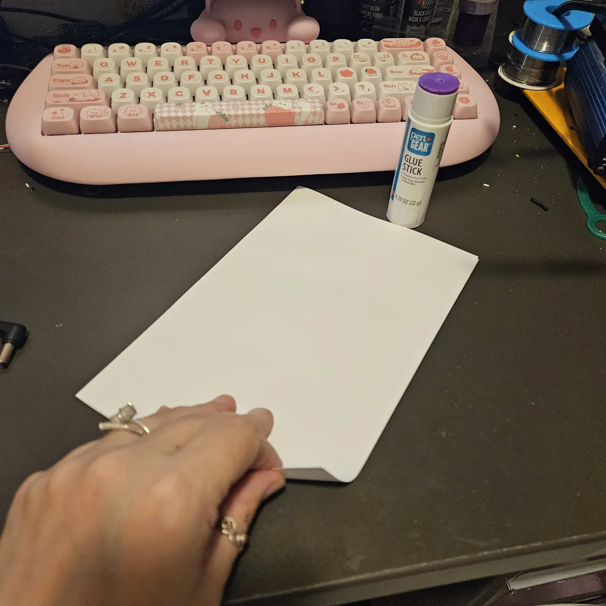 A hand pressing the folded blank sheet flat on the desk.