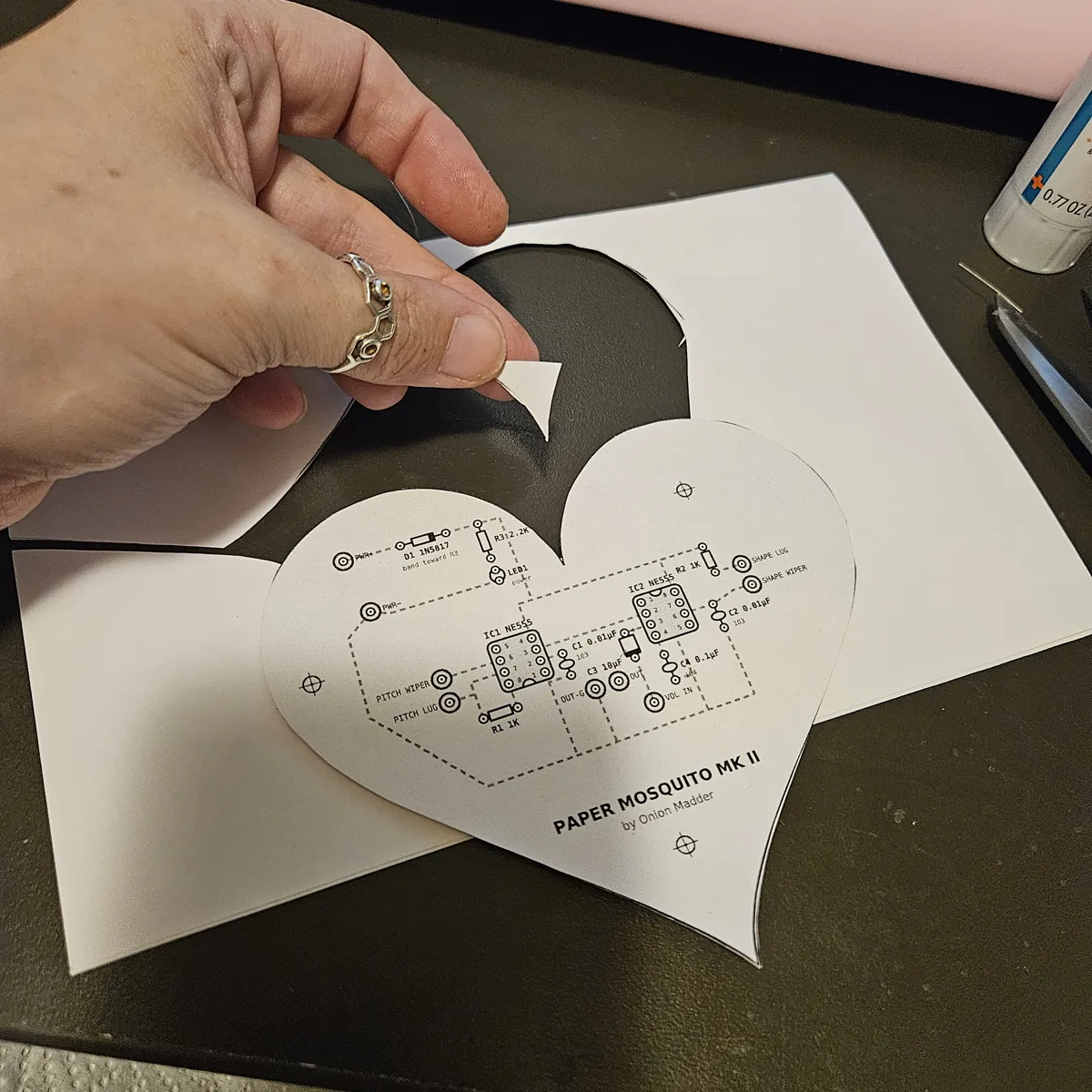 A hand picking a small sliver of leftover core out of the dip at the top of the heart, the cut-away sheet lying beside it.
