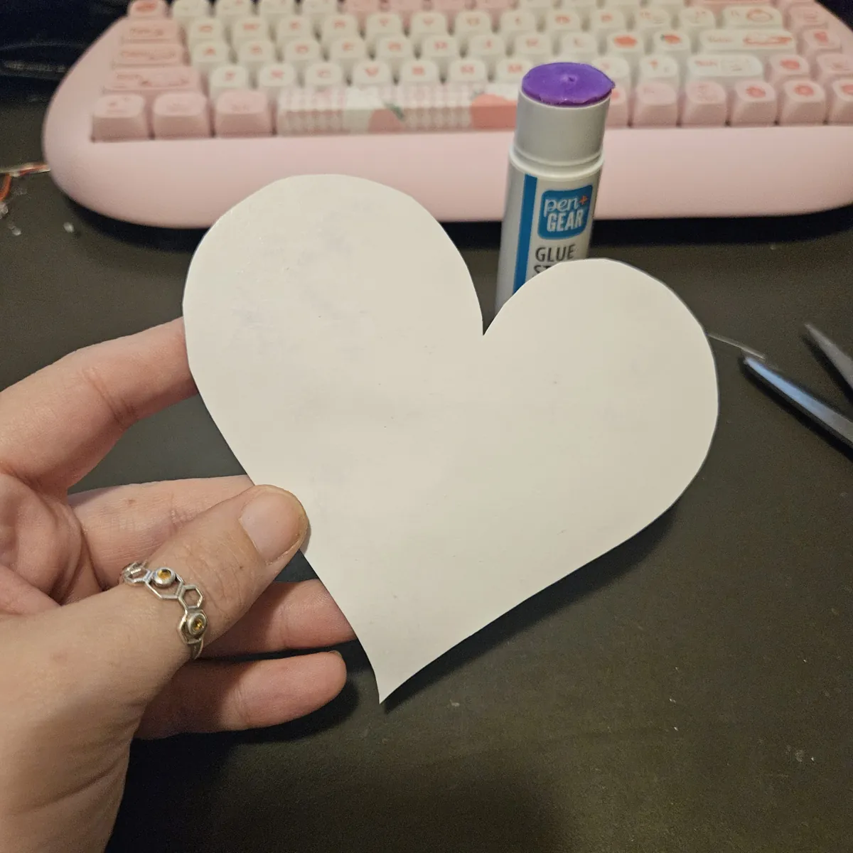 A hand holding the cut-out heart from the back: plain white paper, the bare face of the core.