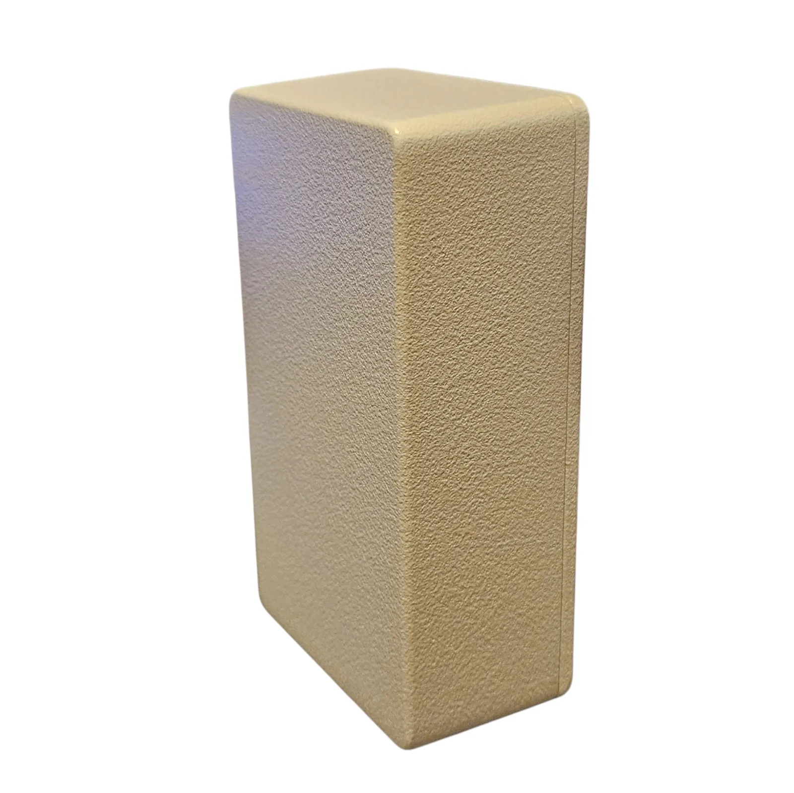The Groaner from the other side at a low angle, the textured sand-colored box standing upright, one plain face and one plain side visible, a faint blue reflection on its top edge.