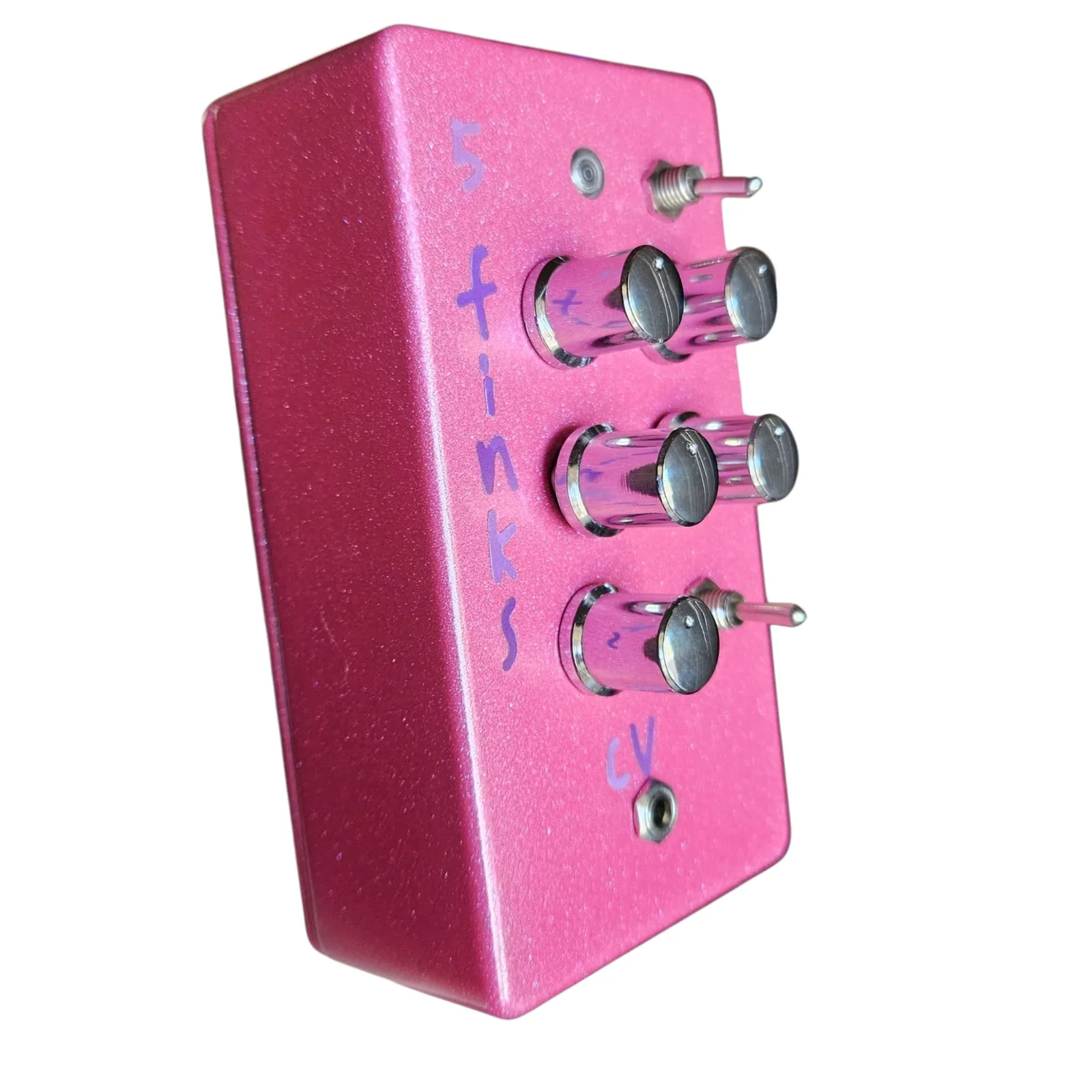 The pink box at a three-quarter angle from the left, the five chrome knobs and two toggles standing off the face and the purple lettering running down beside them.