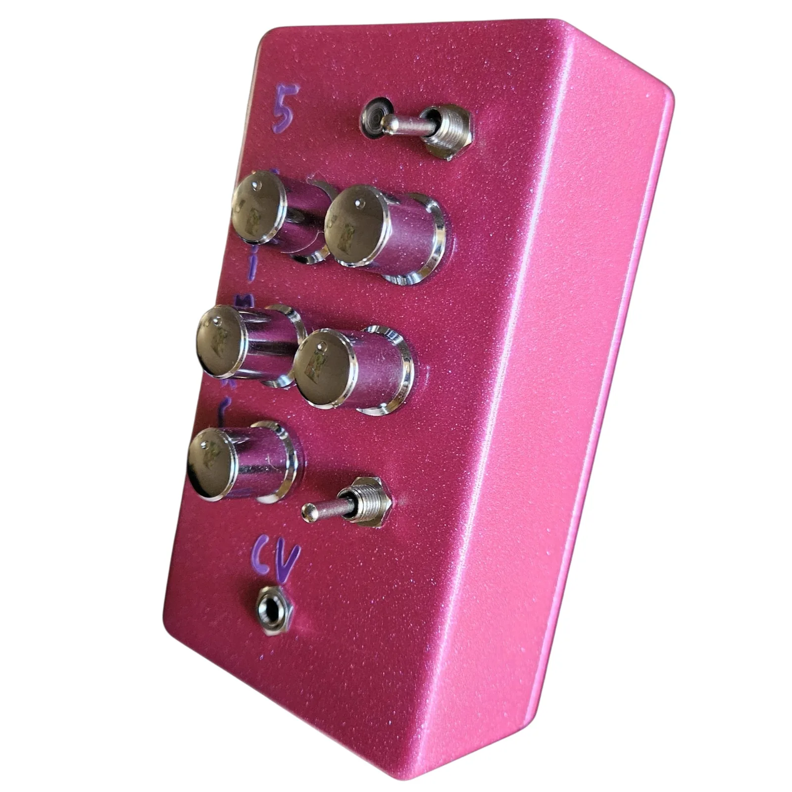 The pink box at a three-quarter angle from the right, the knobs and toggles along the face, the cv lettering and its jack at the bottom, and the long plain side of the box on the right.