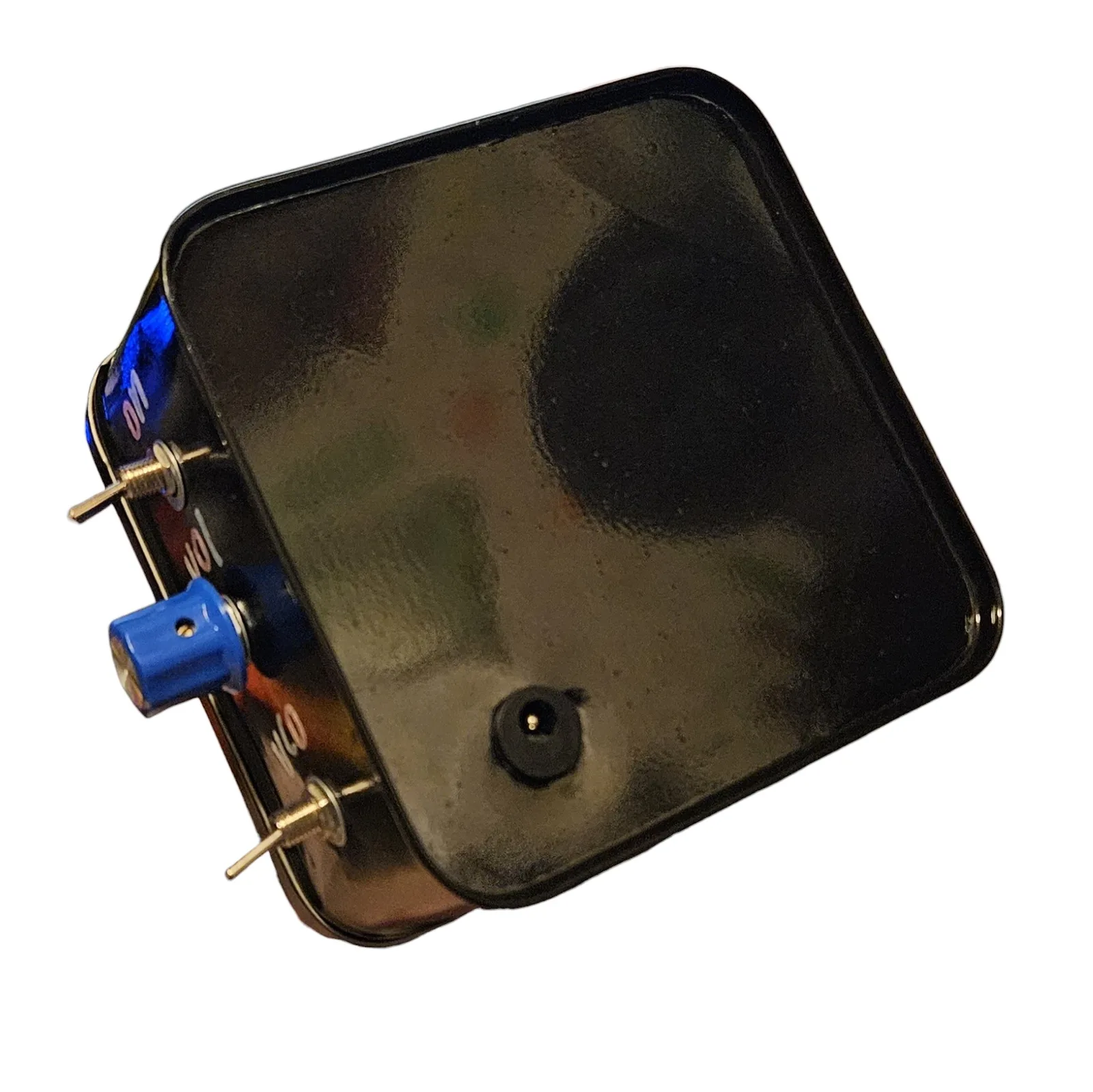 The tin turned to show its glossy black underside with a round black DC jack near one corner, and along the side wall a blue knob between two toggle switches with the labels ON, VOL and VCO in pastel vinyl letters.