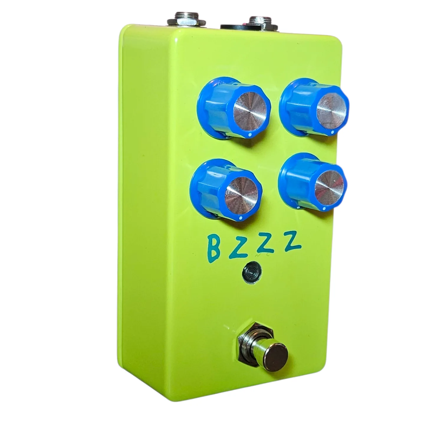 Bzzz pedal, angled left-side view showing the enclosure depth, the 1/4-inch input and output jacks on the top edge, and the knobs foreshortened.