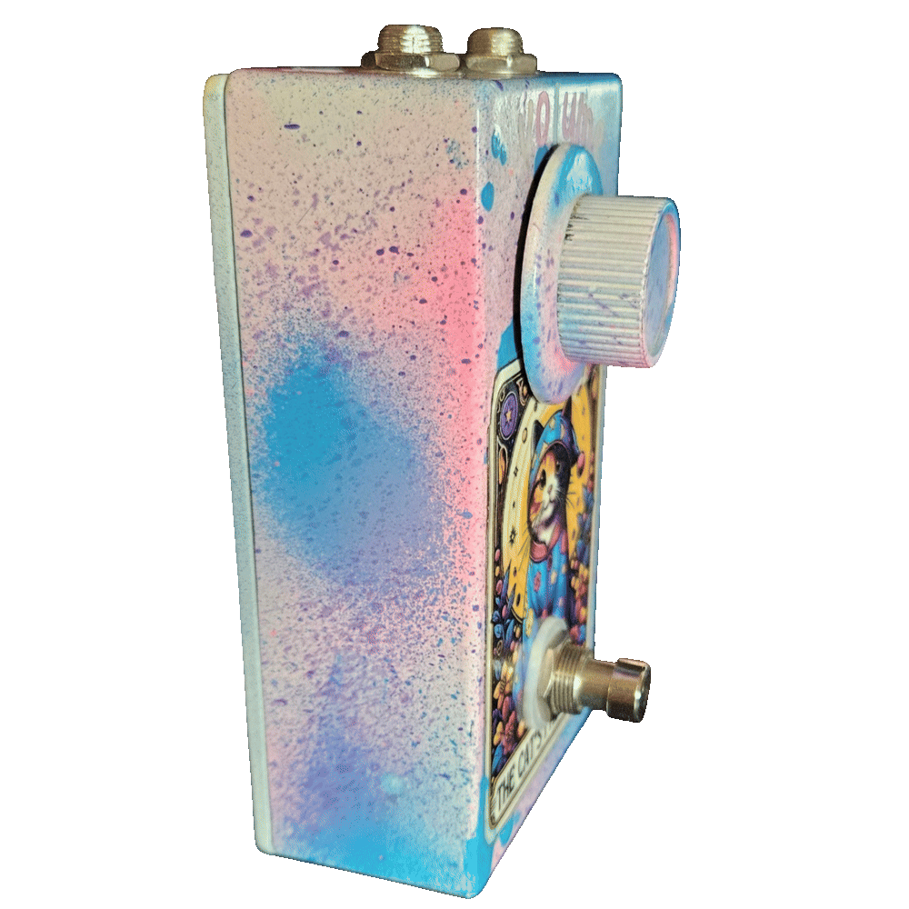 Left side of the pedal: a plain wall of pink, blue, and purple speckle over white with no jacks or controls on this face. The light-blue knob and the footswitch stand well proud of the front, and the two top-edge jacks show along the upper corner.