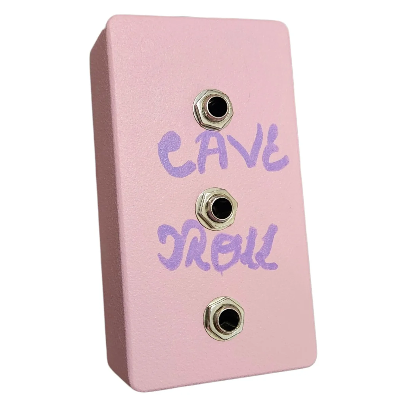 A pale pink pedal photographed at a three-quarter angle. CAVE TROLL is hand-lettered across the face in purple marker in two lines, CAVE above and TROLL below, with three quarter-inch jack sockets running down the face between and below the words, each with a silver hex nut. There are no knobs, no switch and no indicator lamp anywhere on it.