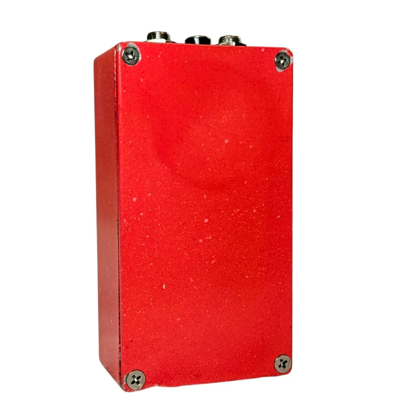 The back of the pedal: a plain red speckled bottom plate with a cross-head screw in each corner, and the jack sockets showing along the top edge.