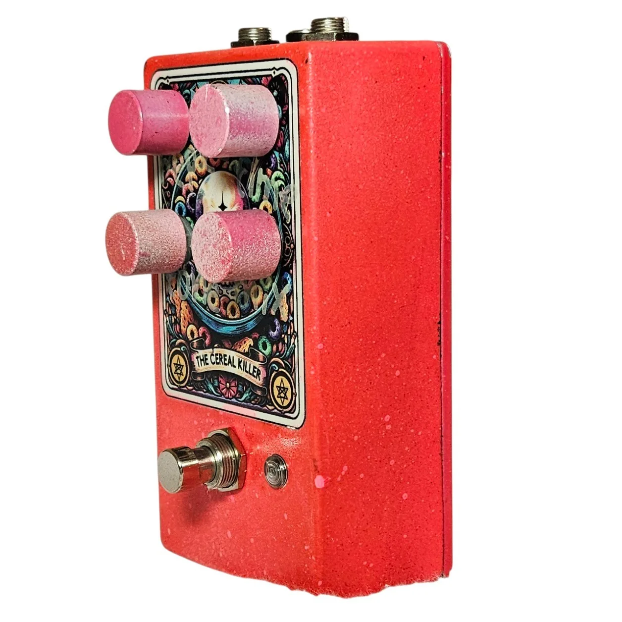 The pedal from the opposite three-quarter angle, the four pink knobs strongly foreshortened across the tarot card and the red enclosure wall filling the frame. The footswitch and LED sit at the lower front corner.