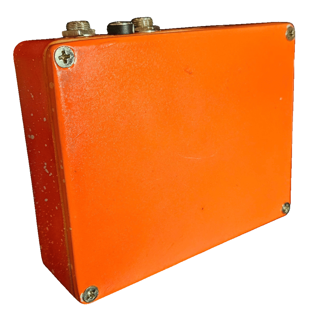 Back of the pedal: a plain glossy orange bottom plate with a Phillips screw in each corner and no label or artwork. The two jacks and the DC socket line the top edge.