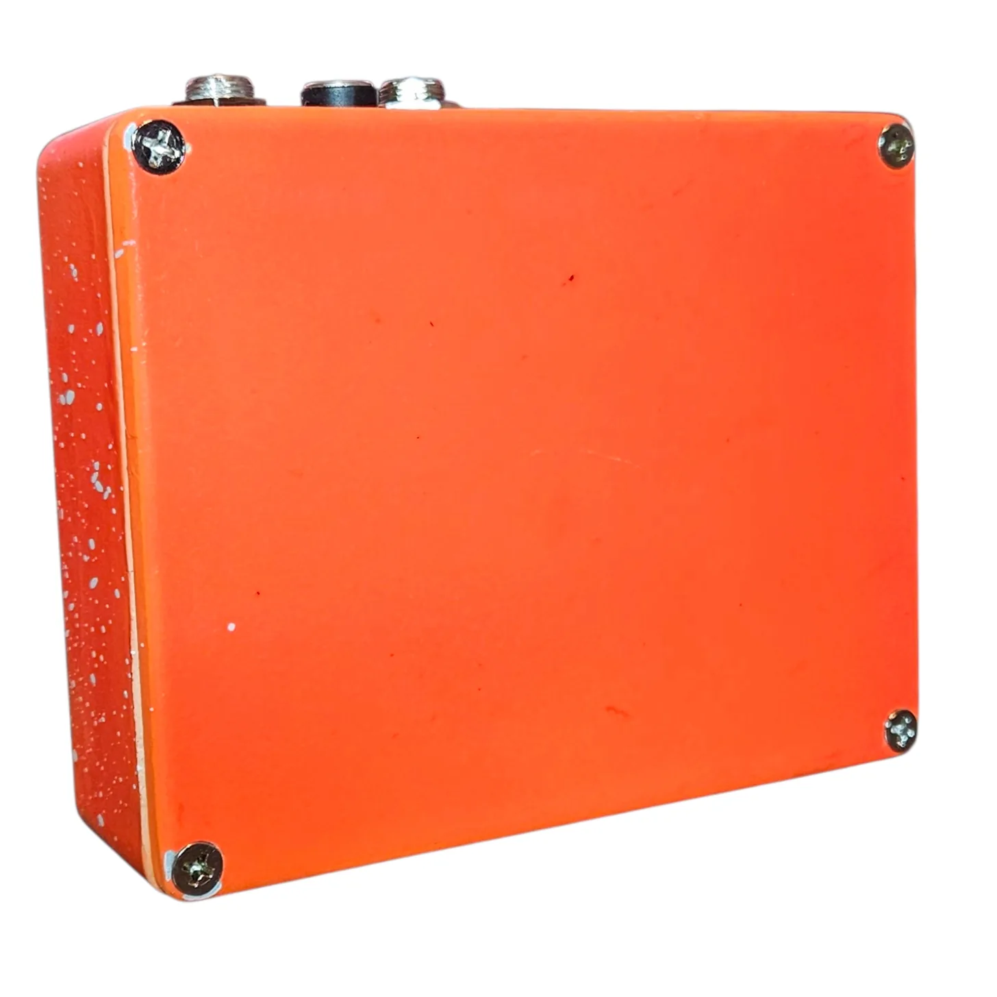 Back of the pedal: a plain glossy orange bottom plate with a Phillips screw in each corner and no label or artwork. The two jacks and the DC socket line the top edge.