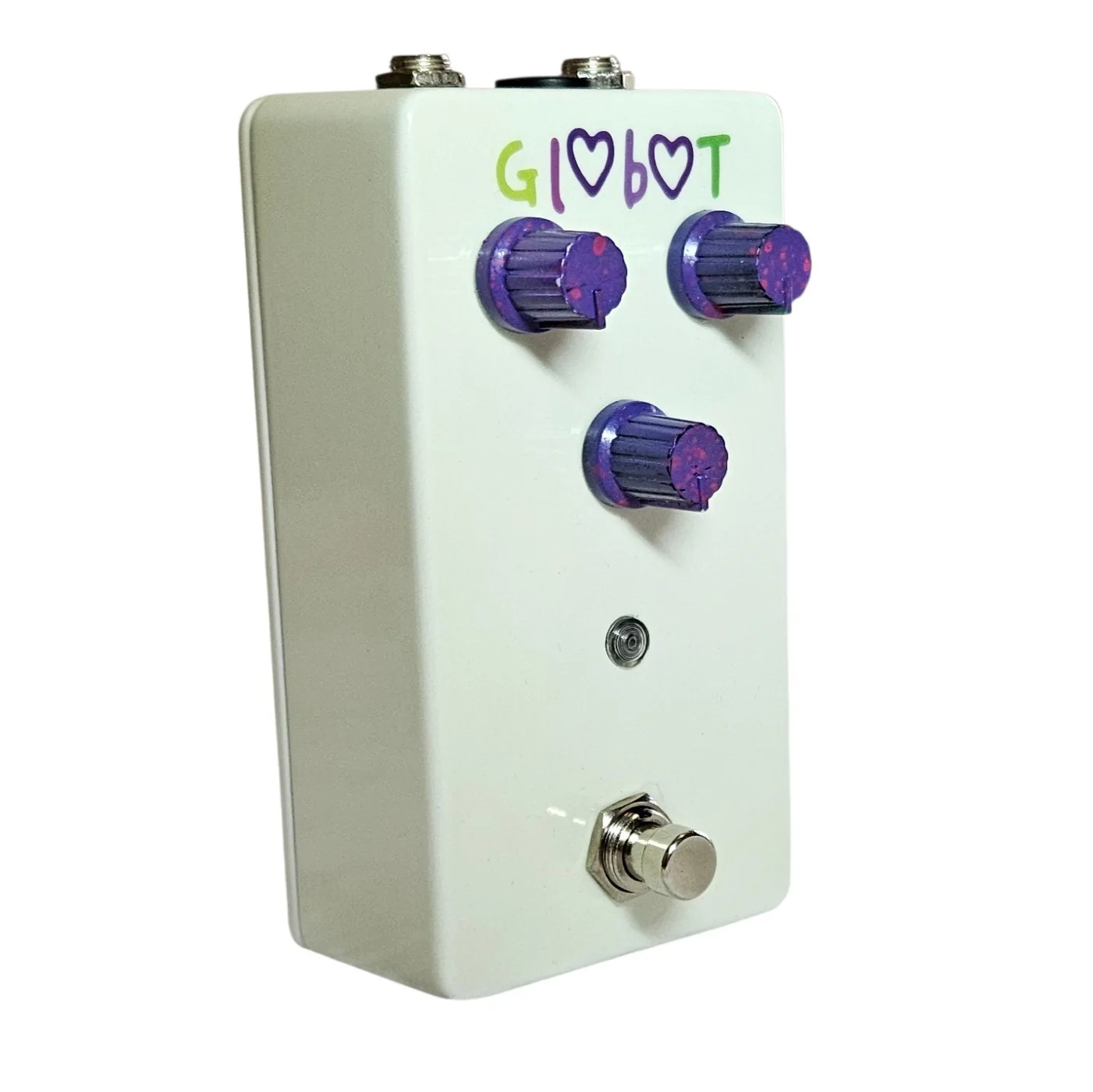 The white pedal turned three quarters to show its depth, the three purple glitter knobs standing off the face in profile and the green and purple lettering still readable along the top.
