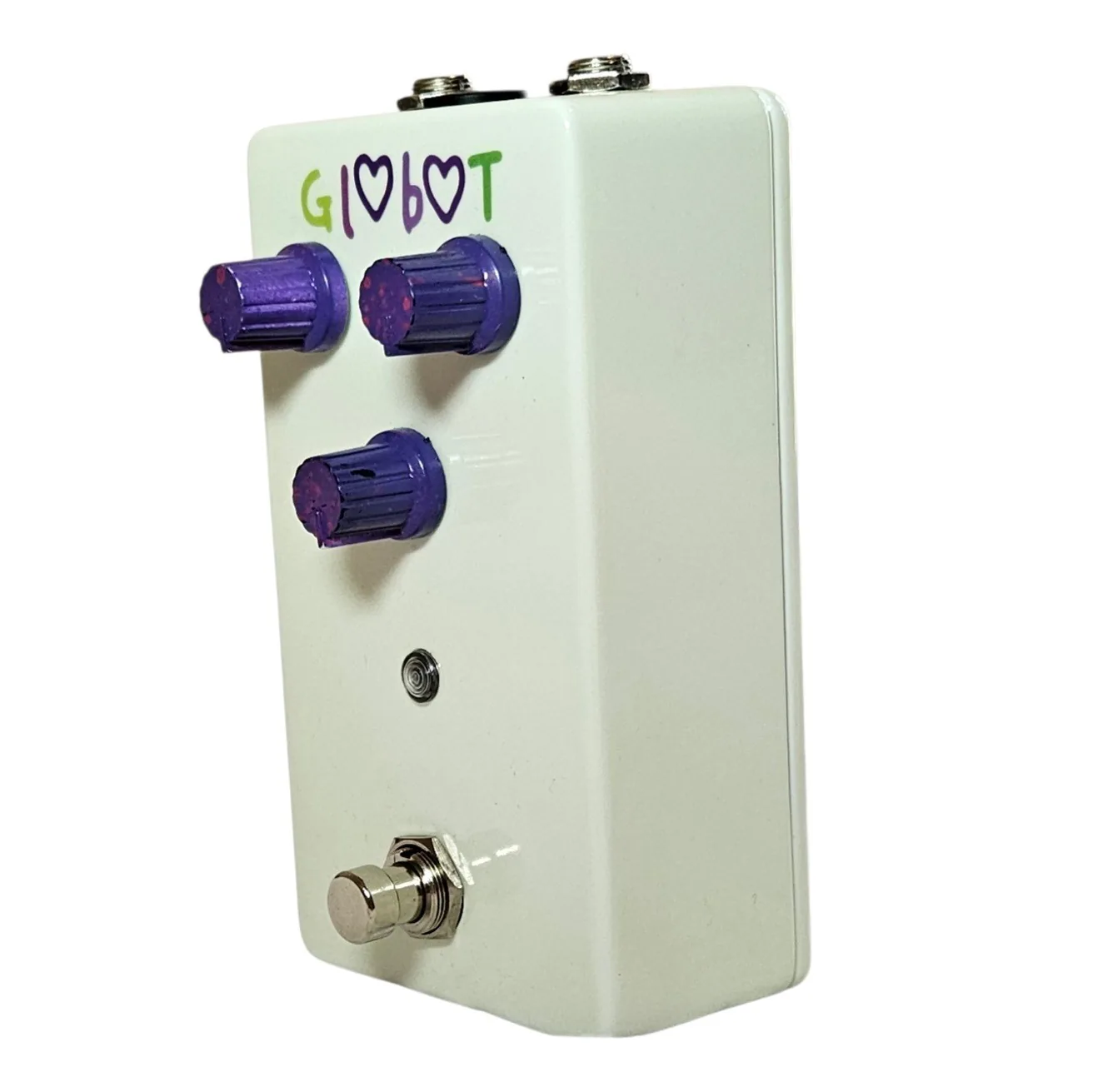 The pedal from the opposite three-quarter angle, the purple knobs foreshortened across the white face and the footswitch projecting from the lower corner.