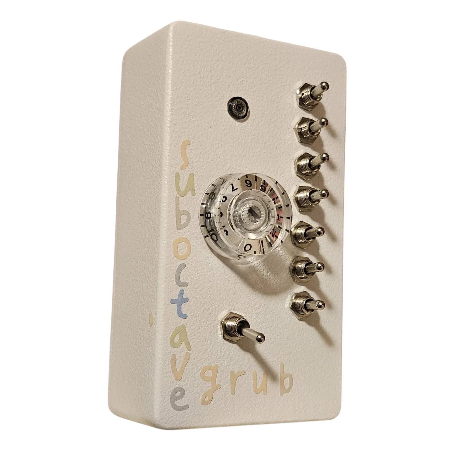 The same box turned at a three-quarter angle with its lettered left edge toward the camera. The seven chrome toggles stand out from the face in a row, the clear numbered knob catches the light, and sub octave reads down the near edge with grub along the bottom.