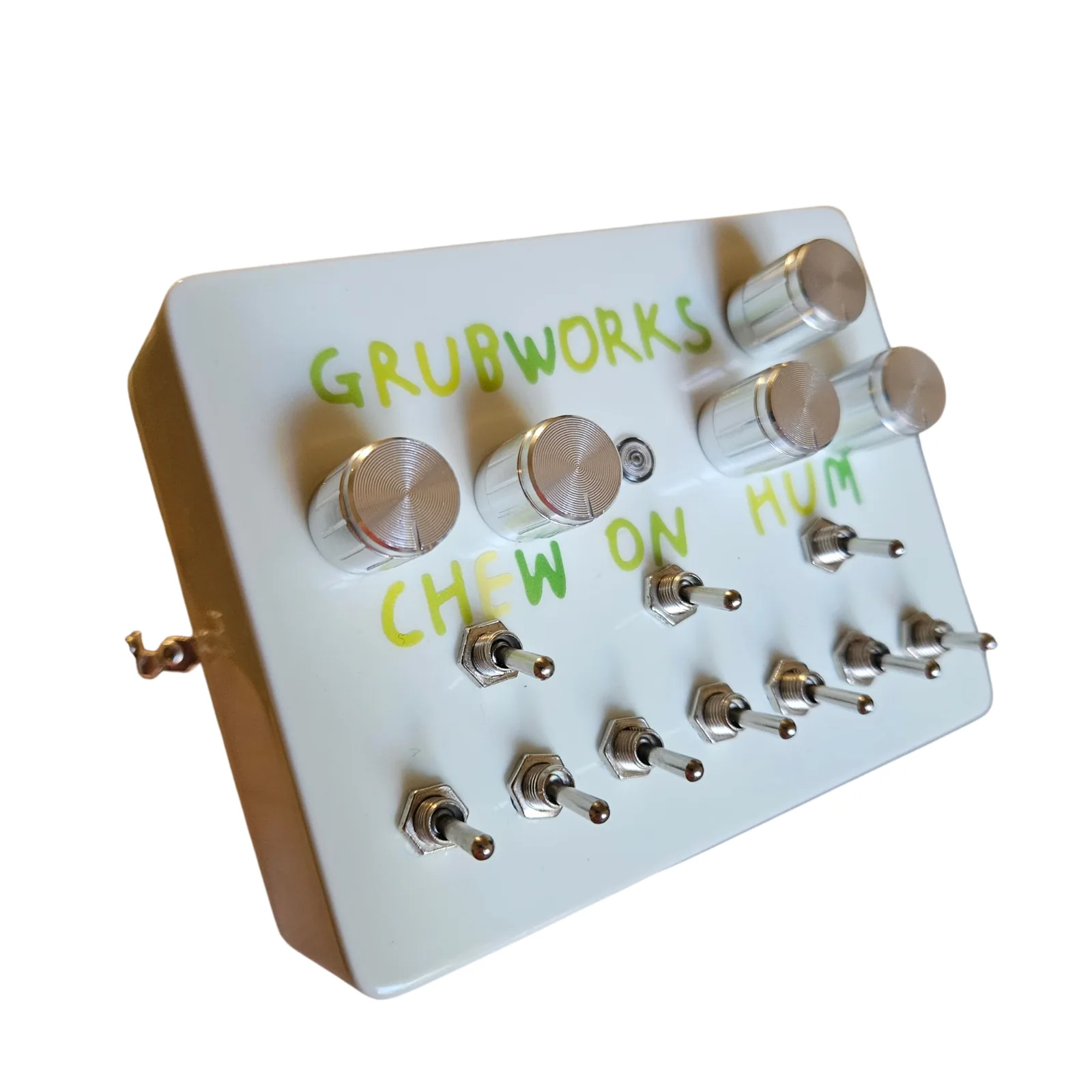 The Grubworks from the left at a three-quarter angle, the white left side toward the camera, the knobs, the CHEW ON HUM lettering and the two rows of toggles on the face.