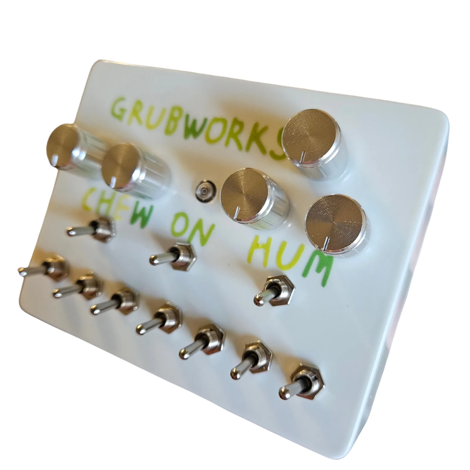 The Grubworks from the right at a three-quarter angle, the white right side toward the camera, with the five chrome knobs, the green lettering and the toggles on the face.