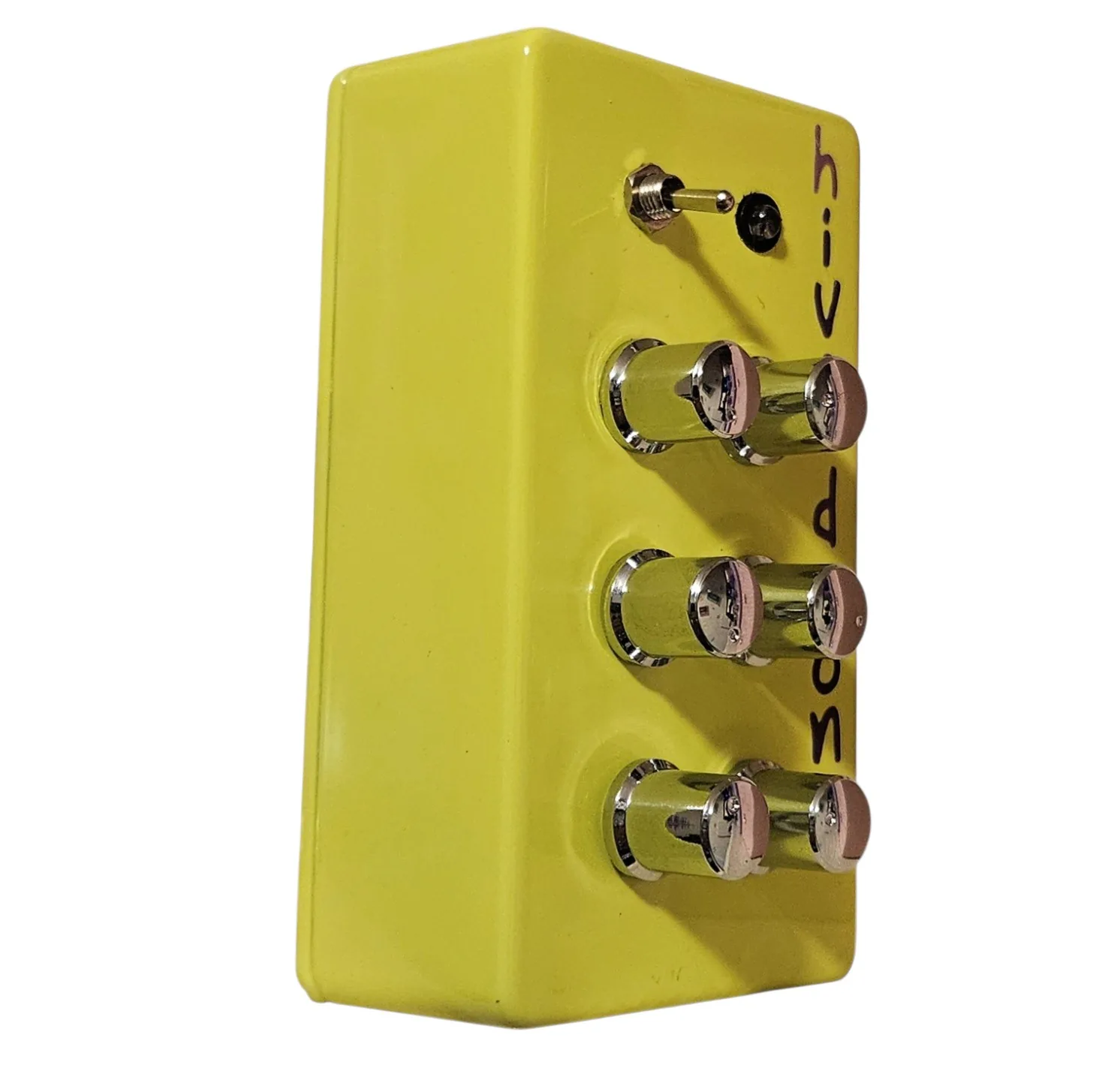 The Hive Drone box from the left at a three-quarter angle, the long neon green side wall toward the camera, the six chrome knobs foreshortened in two columns, the toggle lever at the top and the lettering down the far edge of the face.
