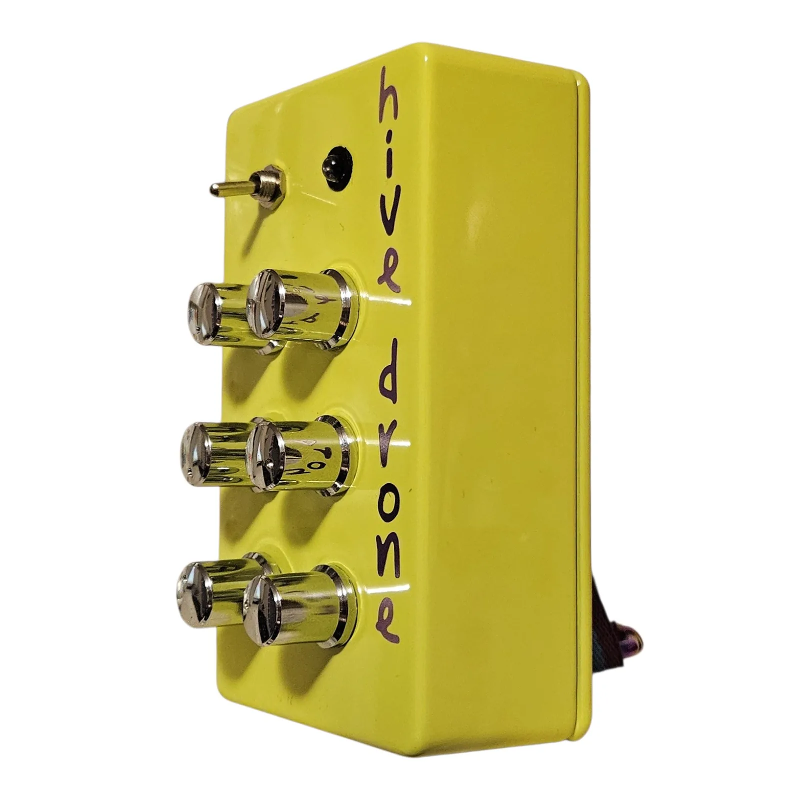 The box from the right at a three-quarter angle: the six chrome knobs stand out from the neon green face in two columns of three, the toggle and the LED bezel above them and the purple lettering along the near edge.