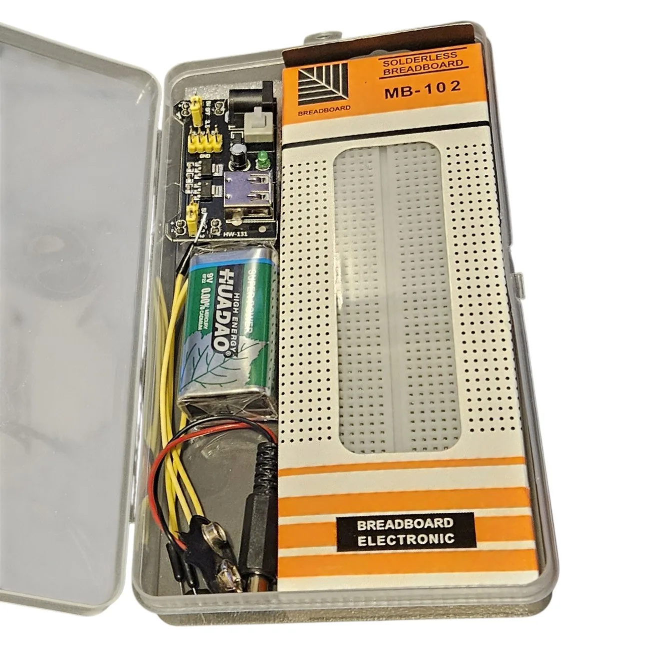 The same case open at an angle with the lid standing up behind it. The breadboard fills most of the base, the green power module is clipped into one end, the nine-volt battery lies beside it and coiled jumper wires are tucked along the bottom edge.