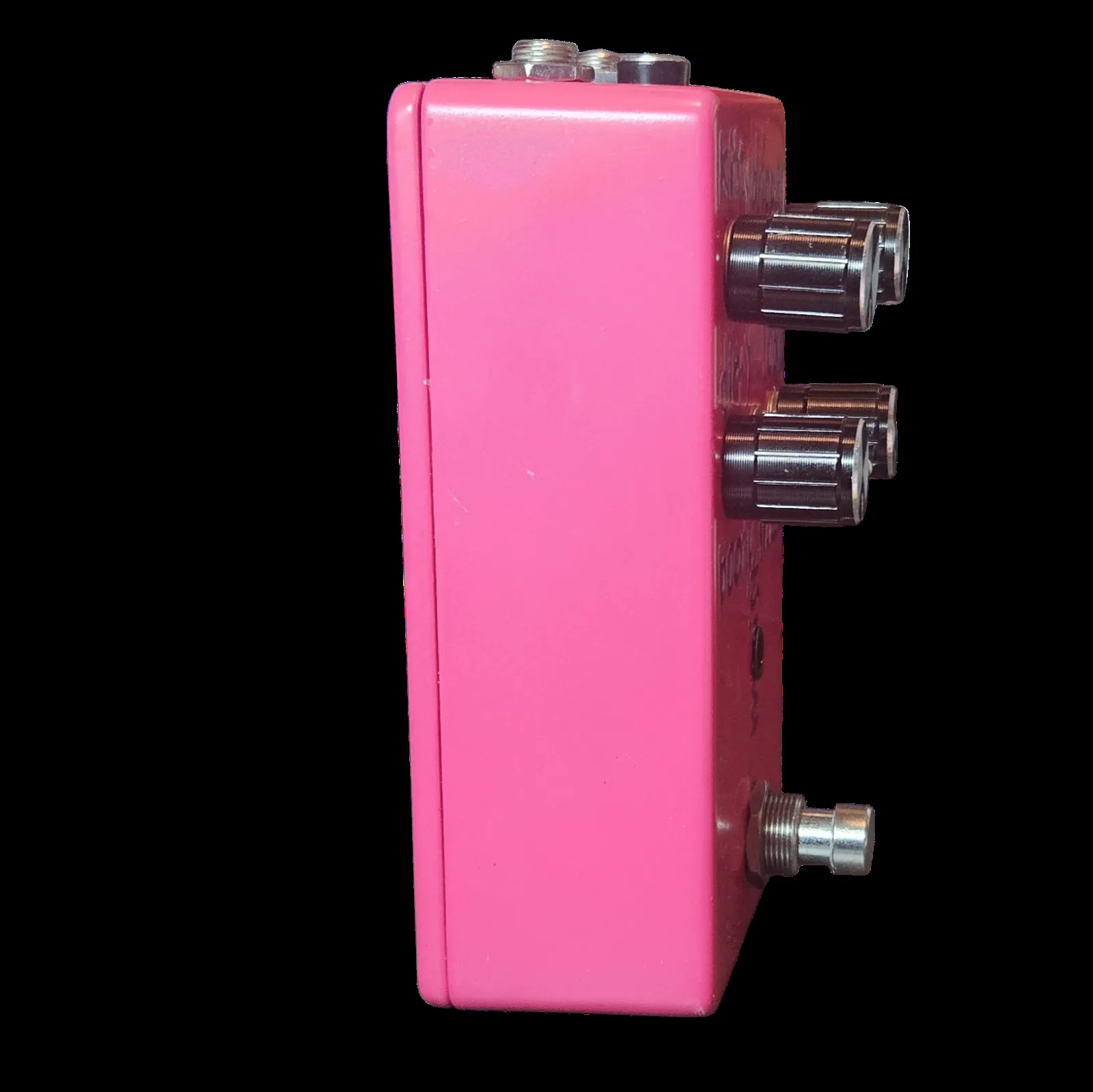 The pedal seen from the side, a plain hot pink flank with no lettering on it. Two quarter-inch jack sockets and a smaller barrel jack for the power supply stand out from the top edge.