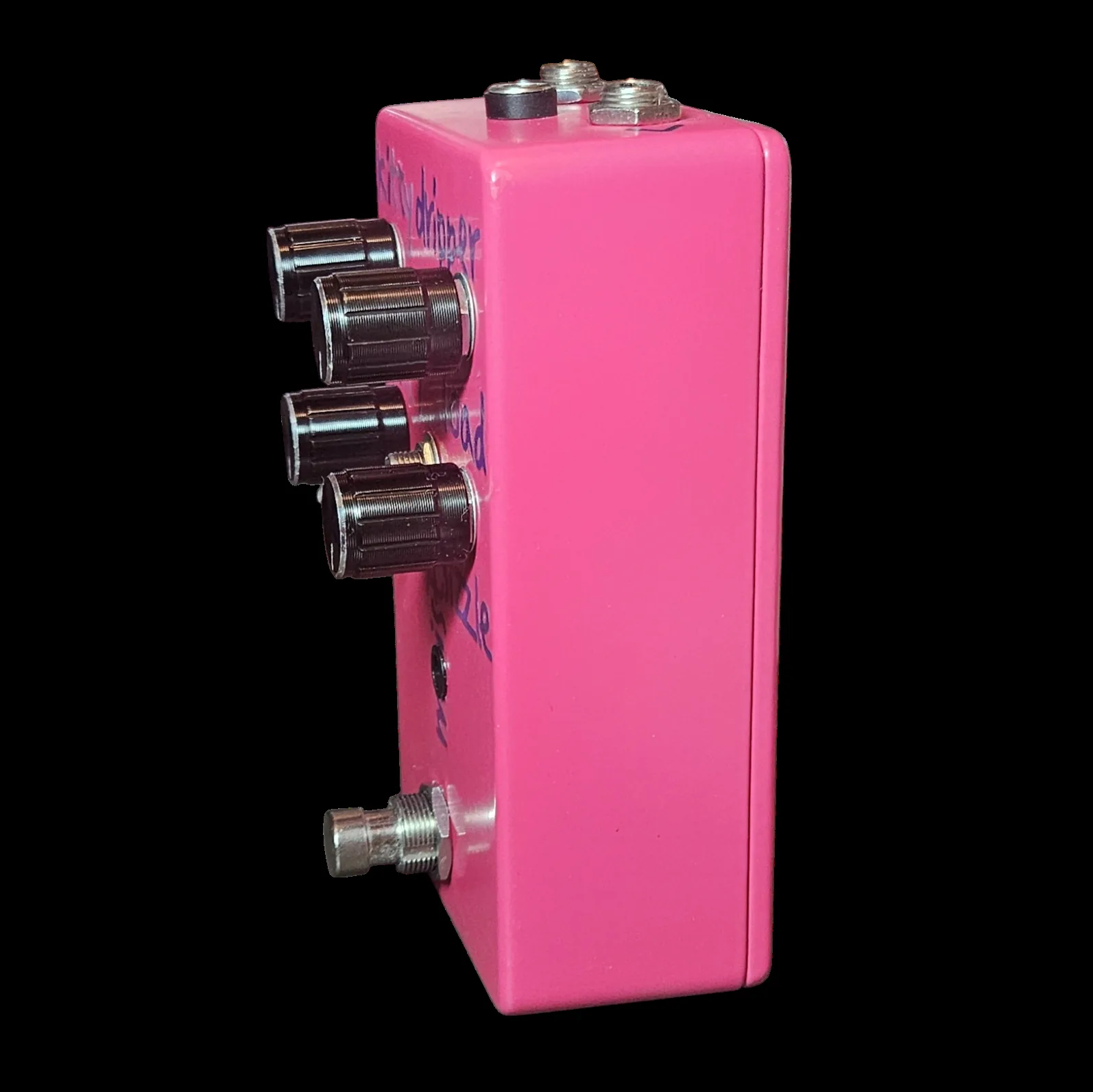 The pedal turned three quarters the other way, the four black knobs standing off the face in profile down one side and a quarter-inch jack visible at the bottom of the top edge. The purple lettering runs down the pink face between the knobs.