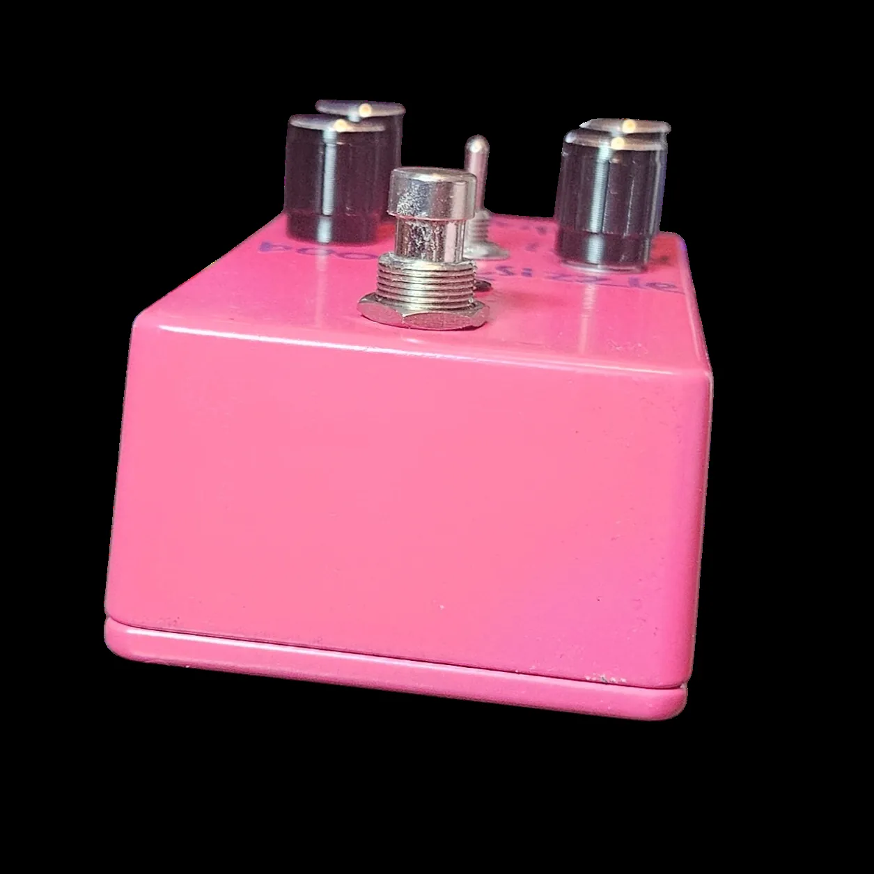 The pedal tilted back and shot from its lower edge, so the broad pink flank fills the frame and the footswitch collar stands up in the middle of the top with two knobs either side of it. The purple lettering is visible along the face but foreshortened.
