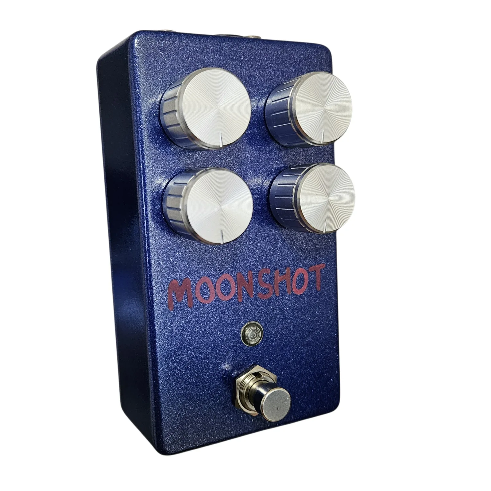 The Moonshot pedal stood upright and seen from the front left on white. A blue sparkle 125B enclosure with four silver knurled knobs in a two by two square, the word MOONSHOT hand-lettered across the face in red marker below them, a small indicator lens under the lettering and a silver footswitch at the bottom.