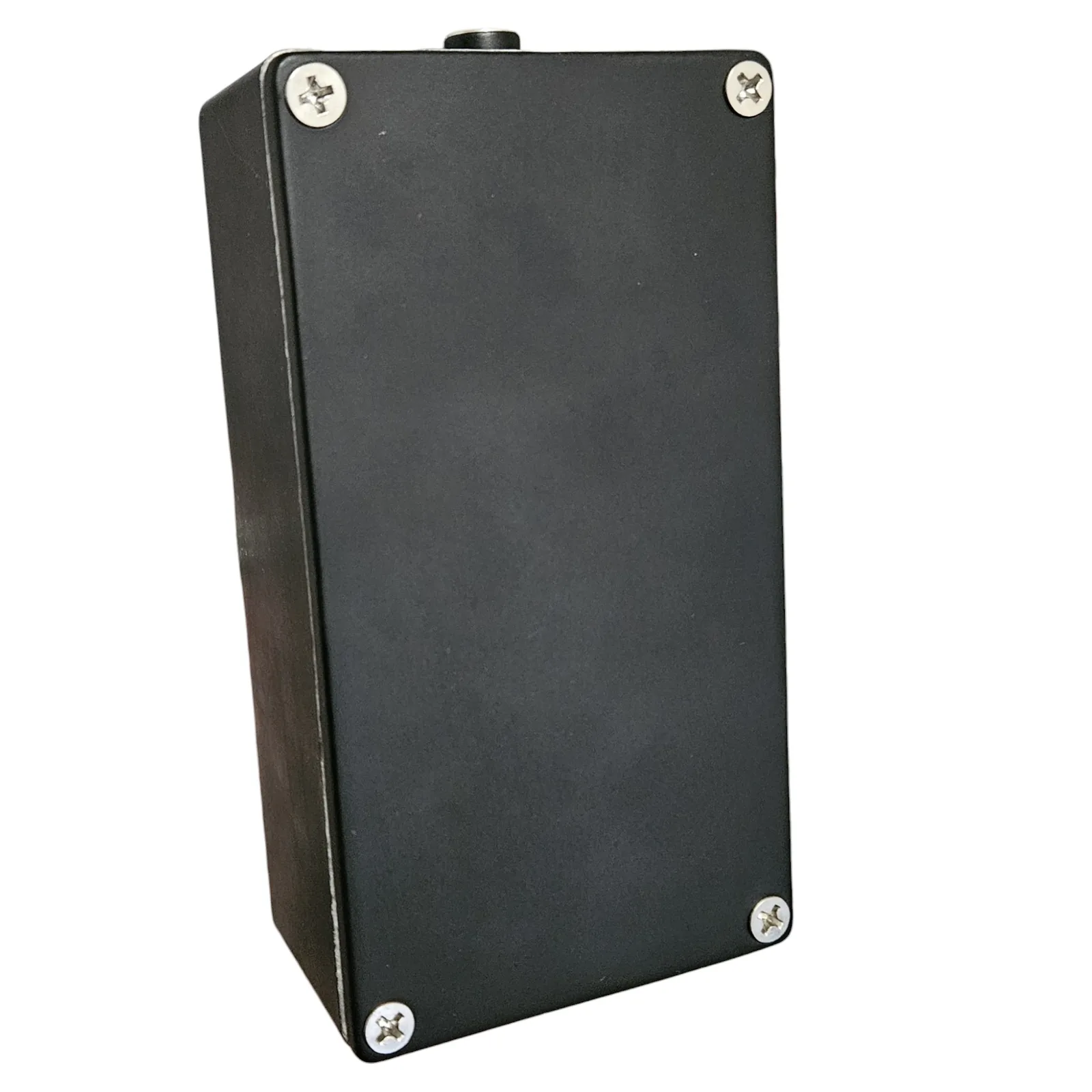 The back of the pedal, a plain black plate with no lettering on it, held on by four silver cross-head screws, one at each corner. The barrel of the power jack shows at the top edge.
