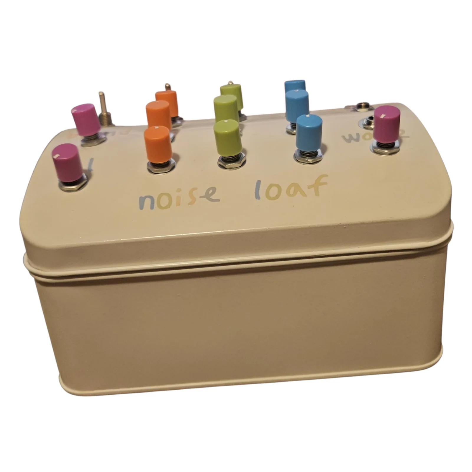 The tin seen almost side on, showing how deep it is: a plain cream-painted box with a rim around the middle where the lid meets the base, and the twelve knobs and three toggle levers standing along the top like a skyline. The words noise loaf are lettered across the sloping lid.