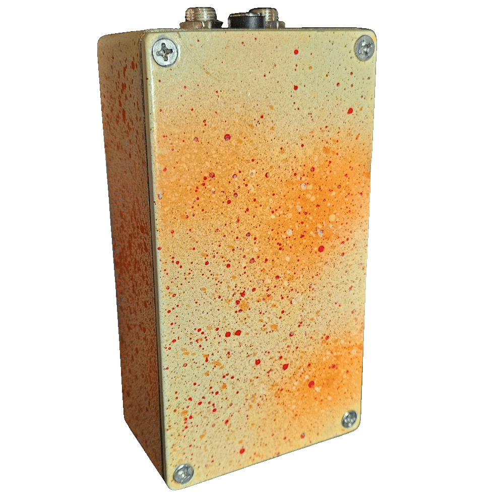 Back of the pedal: the bottom plate is cream misted with orange and spattered with fine red dots, with a Phillips screw in each corner and no label. The jacks and DC socket show along the top edge.