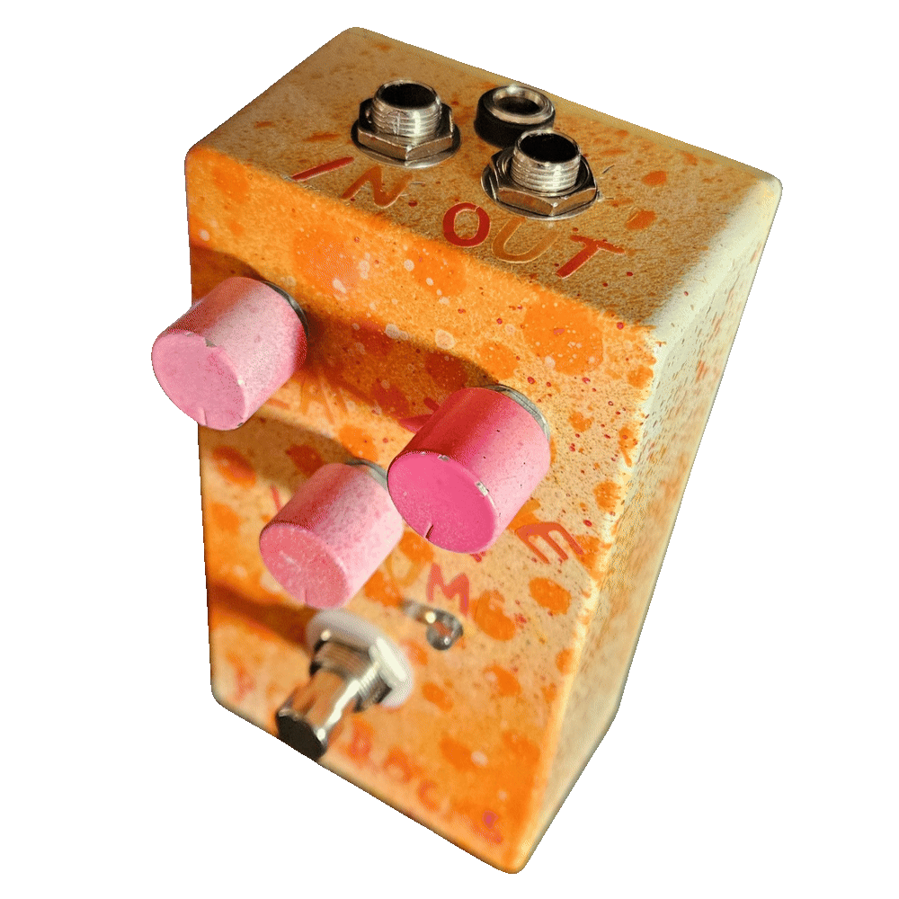 Top-down view of the enclosure: hand-lettered orange "IN" marks the left 1/4-inch jack and "OUT" the right, with a DC power jack set between and slightly behind them. The three pink knobs and the footswitch fall away below.