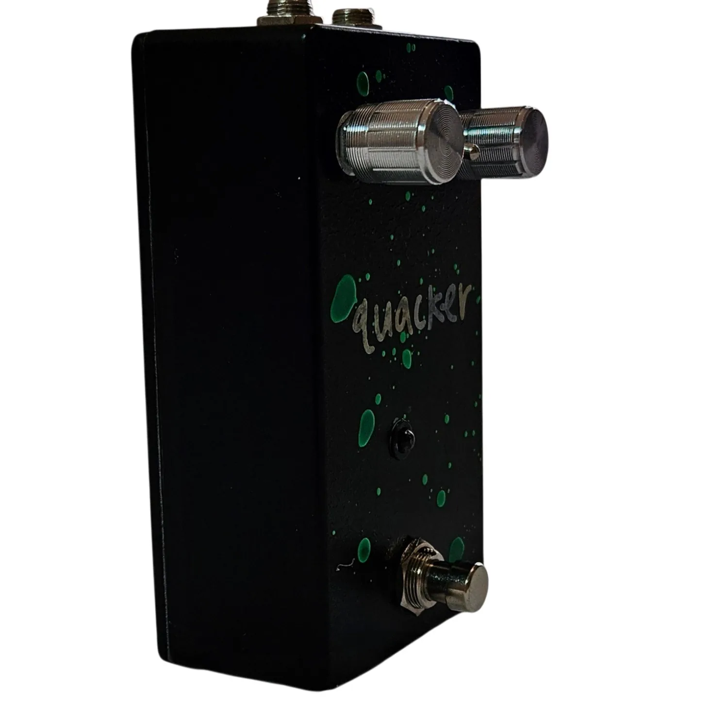 The green-spattered pedal turned three quarters, one knurled silver knob projecting from the top edge toward the camera and the silver quacker script running down the face.