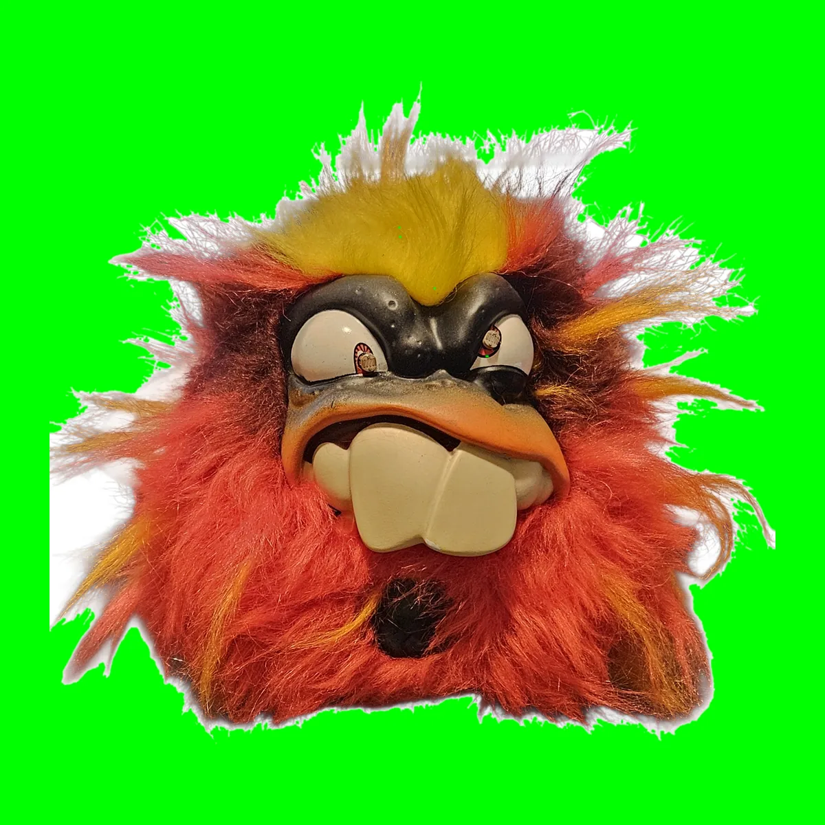A round toy monster covered in shaggy red, orange and yellow fur with a hard plastic scowling face and dark photocells set into its eyes