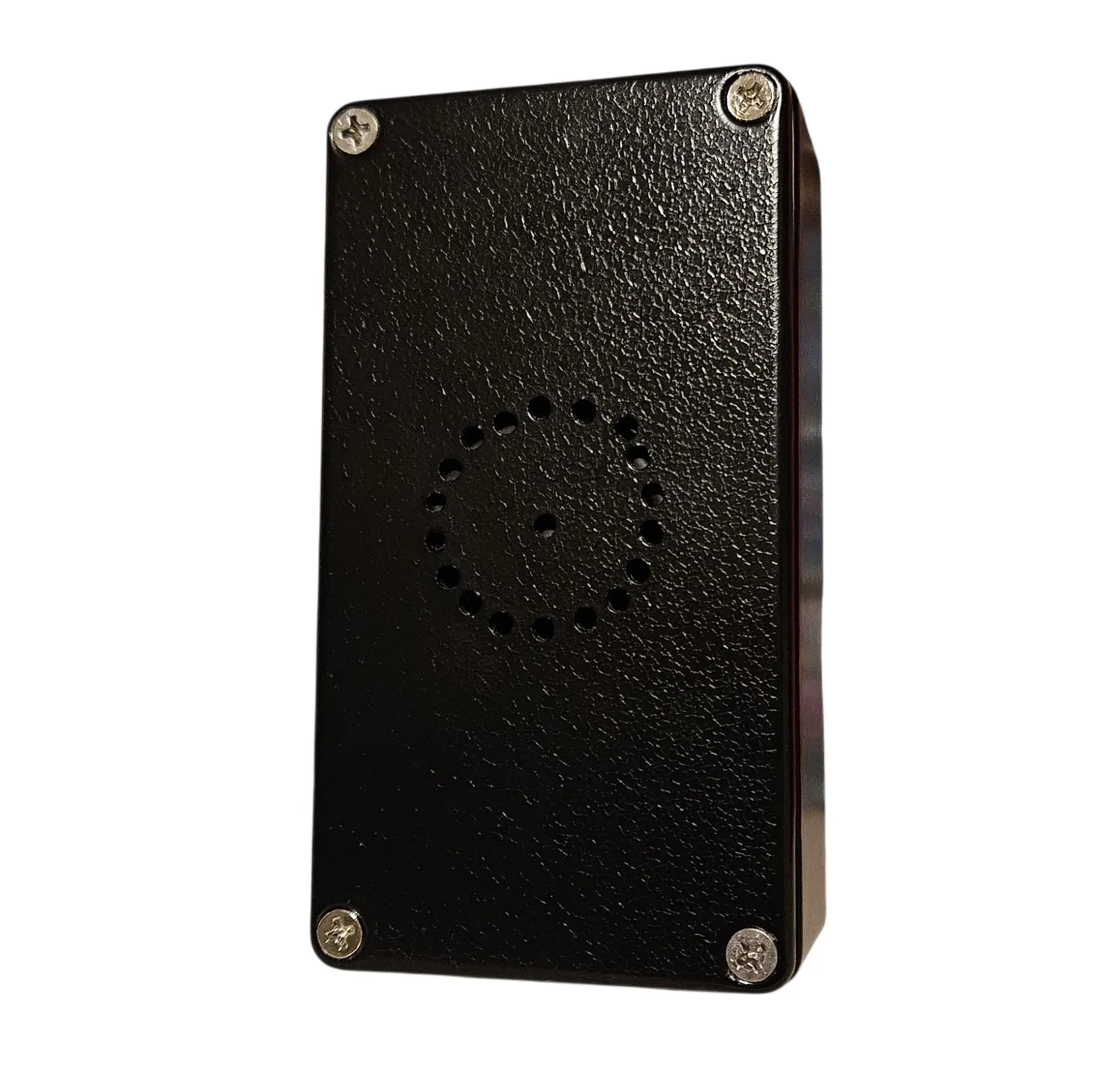 The back of the box: a textured black plate with a Phillips screw in each corner and, in the middle, a ring of small drilled holes around a single center hole - a speaker grille cut by hand.