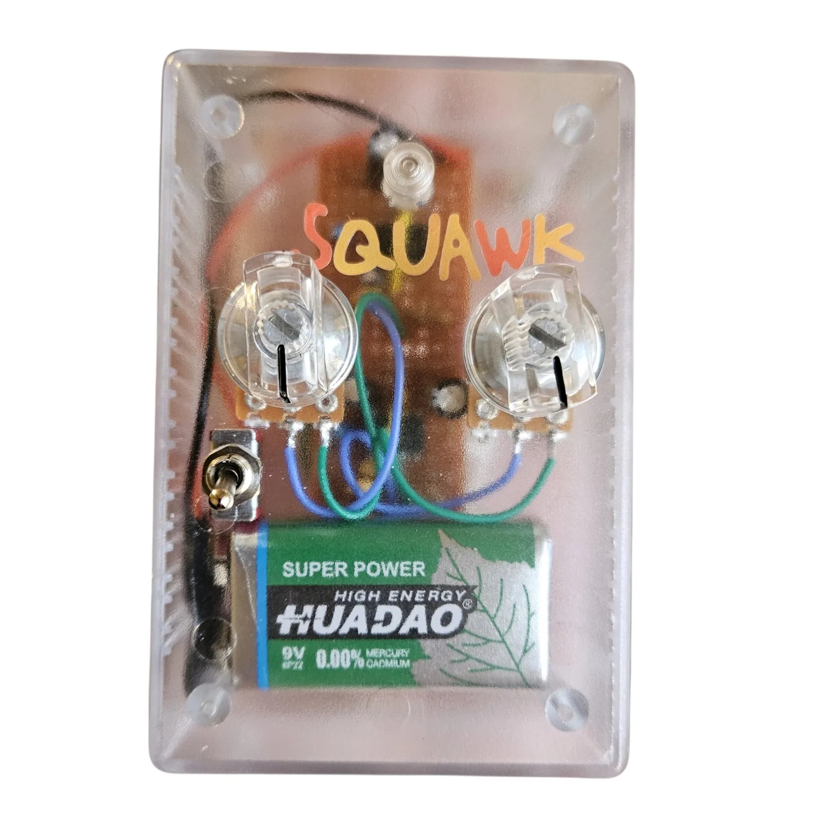 A clear plastic box seen face on, so everything inside shows through. Squawk is hand-lettered across the top in orange and yellow. Two clear knobs sit side by side on the lid with their pots and a small piece of perfboard underneath, blue and green wires loop between them, a small toggle sits at the left edge, and a green 9V battery fills the bottom of the box.