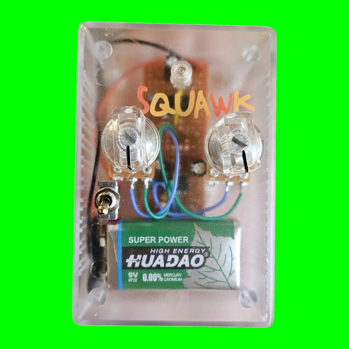 A clear plastic box seen face on, so everything inside shows through. Squawk is hand-lettered across the top in orange and yellow. Two clear knobs sit side by side on the lid with their pots and a small piece of perfboard underneath, blue and green wires loop between them, a small toggle sits at the left edge, and a green 9V battery fills the bottom of the box.