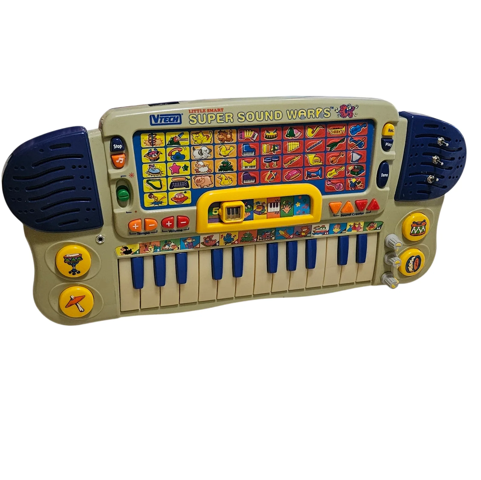 The keyboard against white, tilted at an angle and seen from slightly above: a long cream toy keyboard with dark blue teardrop speaker grilles at each end and twenty-five cream and dark blue keys. Across the top the toy's own logo reads VTech Little Smart SUPER SOUND WARPS, the last word redrawn in the original yellow outlined lettering so it matches the factory printing. Below it is a grid of five rows of small picture buttons showing instruments and animals, with Stop and music-note buttons, a green slider, orange Tempo and red Volume buttons, a yellow Activities selector, Rec, Play and Demo buttons, four orange and red Sound Creator triangles, and four round yellow drum pads printed with drums. Added to it are three silver toggle switches set straight through the right-hand speaker grille, three small knurled knobs with yellow pointers down the right edge, and a metal jack socket at the left.