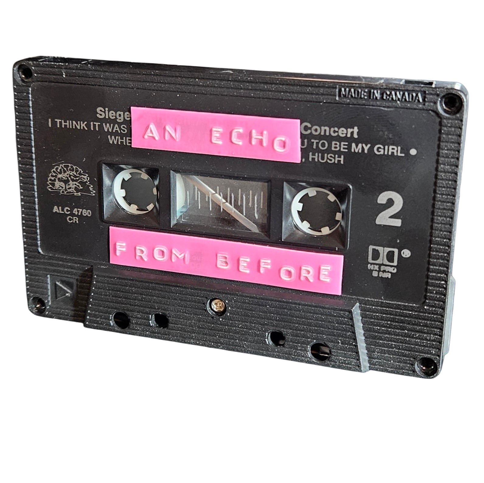 Black cassette shell with two pink hand-lettered labels reading An Echo and From Before, recycled from an old concert cassette