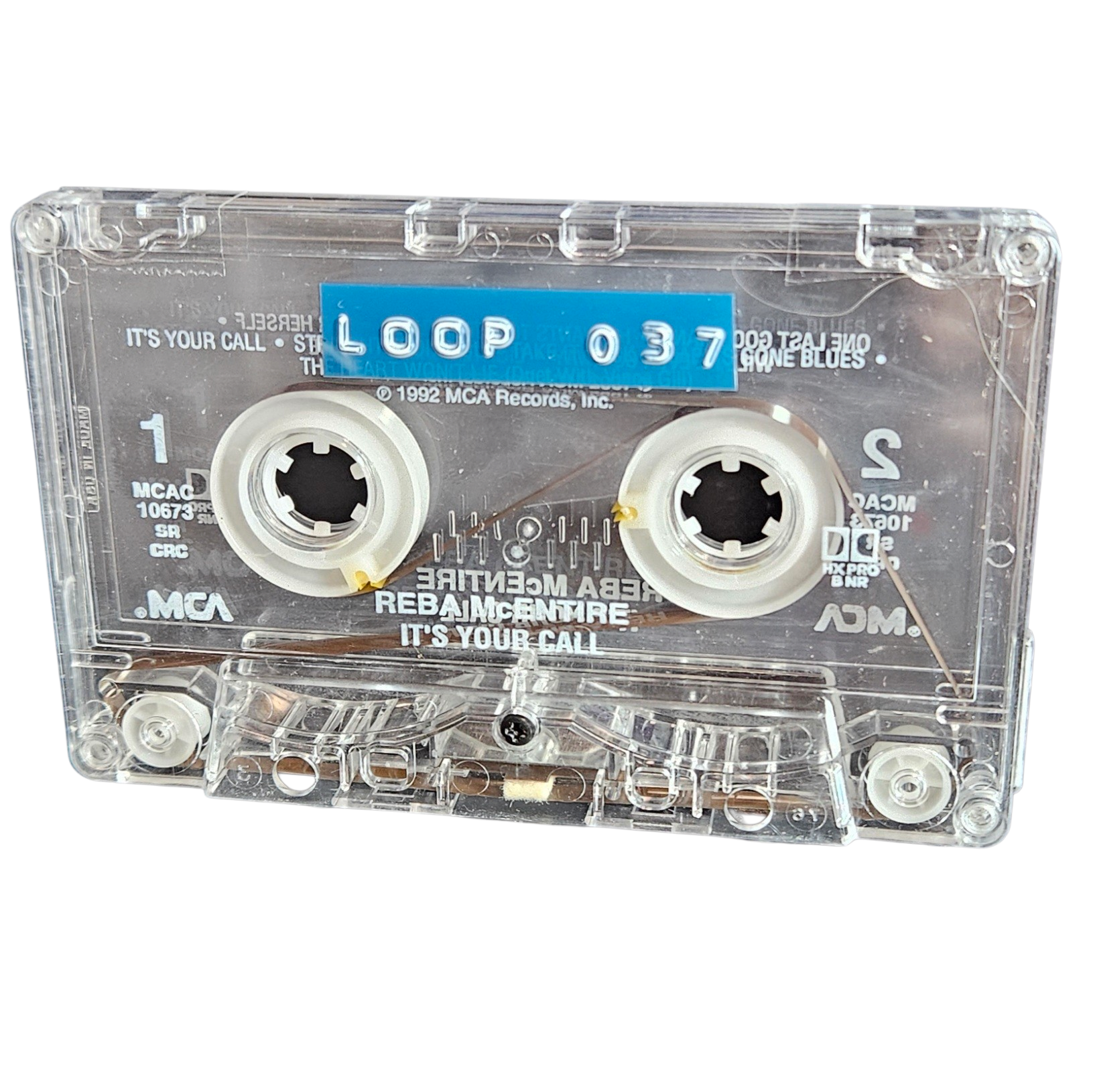 Clear cassette shell labeled Loop 037 on a blue strip, recycled from Reba McEntire's It's Your Call cassette