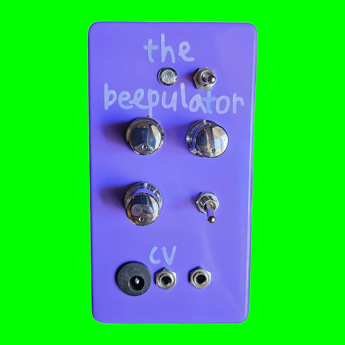 A glossy purple box stood upright, seen face on. the beepulator is hand-lettered across the top in pale lilac. Below it an indicator LED and a small toggle, then two chrome knobs side by side, a third chrome knob with a second toggle beside it, cv lettered underneath, and three jacks in a row along the bottom: the barrel power jack, the CV in and the line out.