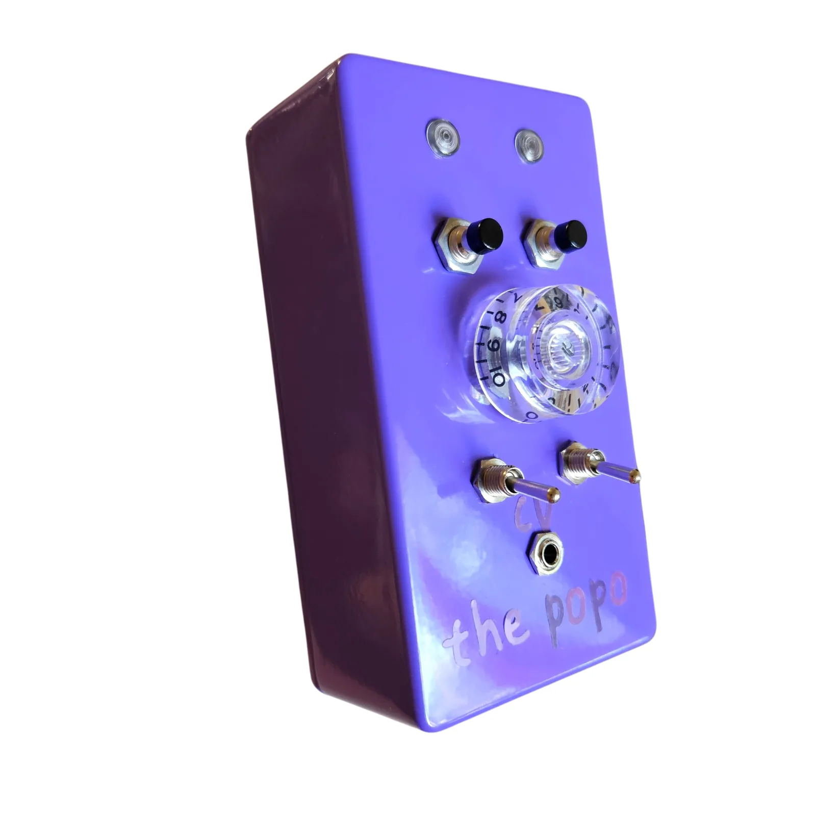 The Popo from the left at a three-quarter angle, the purple left side toward the camera, the lights, the buttons, the clear knob, the toggles and the jack on the face.
