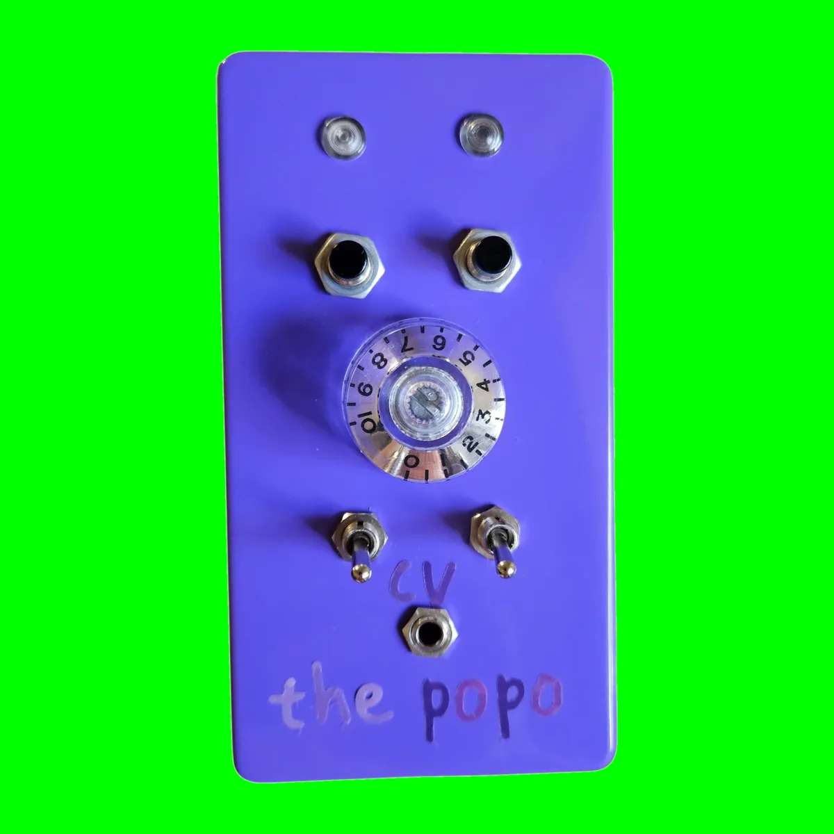An upright glossy purple box photographed face on. Two clear lights sit side by side at the top, two black push buttons below them, and a large clear knob with a numbered skirt in the middle. Under the knob are two toggles with cv lettered between them over a small jack, and the popo is hand-lettered across the bottom in pink and purple.