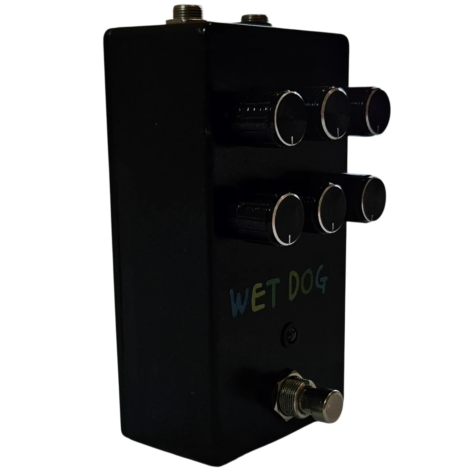 The pedal turned three quarters to show its depth, the six black knobs projecting well off the face in two rows and the WET DOG lettering still readable below them. Jack sockets show along the top edge and the footswitch stands at the near corner.