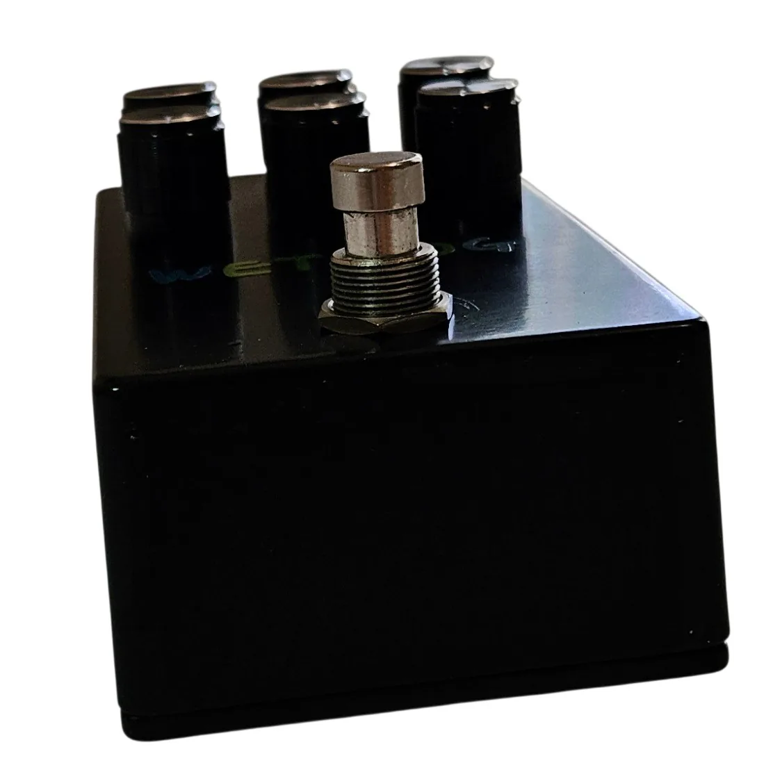 Looking down on the pedal from the footswitch end: the six black knobs stand in two rows along the far edge, the silver footswitch nut rises in the middle, and the plain black wall of the enclosure fills the lower half.